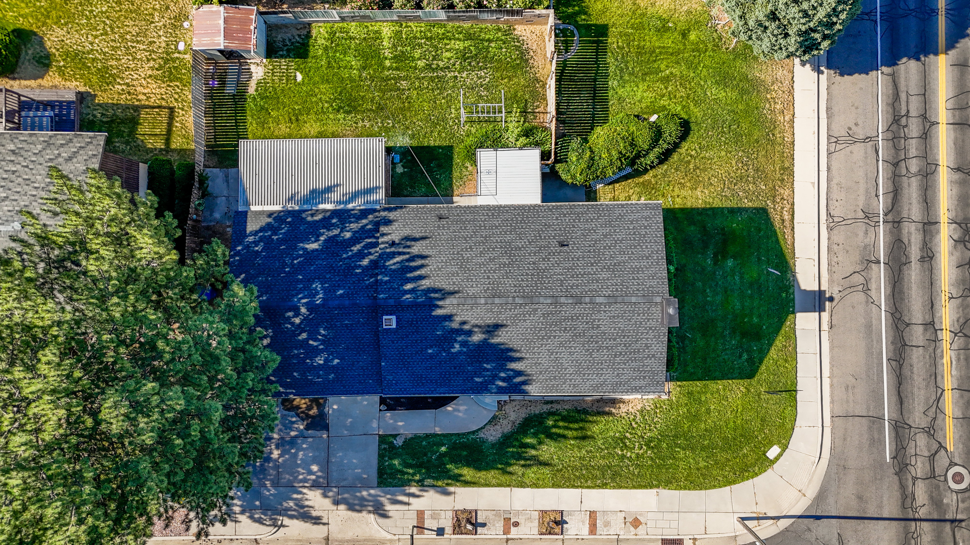 Asphalt shingle roof, established landscaping, concrete pathways, and an adjacent street