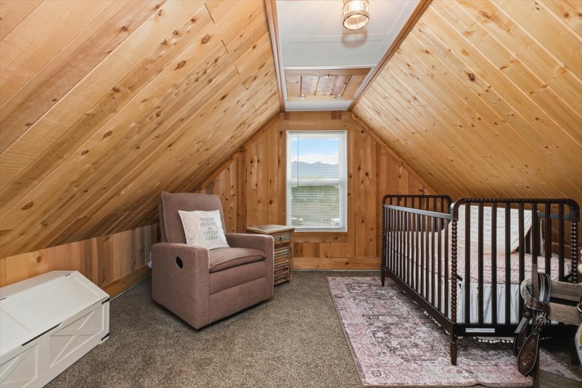 Attic room featuring sloped wood-paneled walls and a window offering a distant mountain landscape