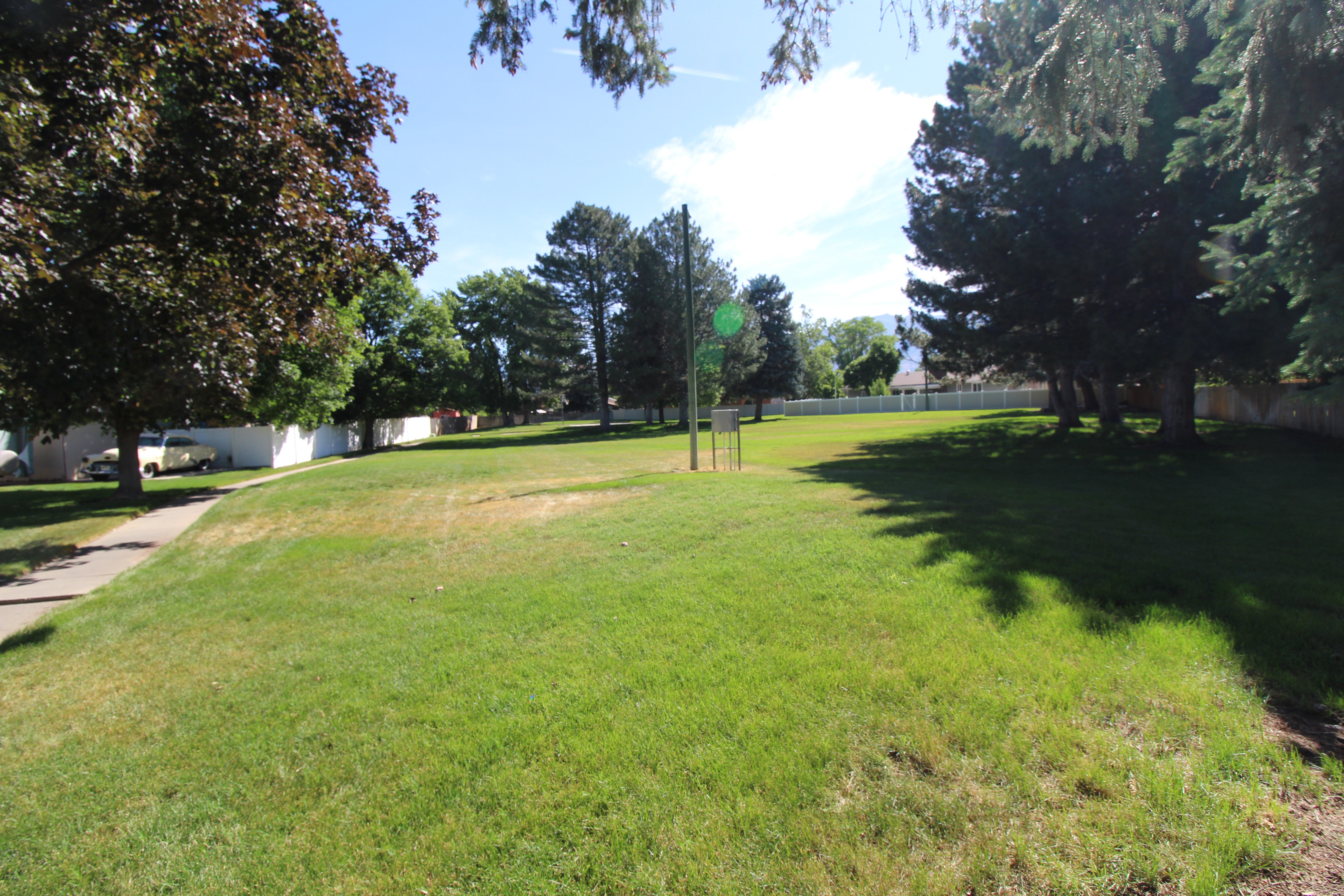 Expansive green space featuring a park with mature trees and a paved walkway