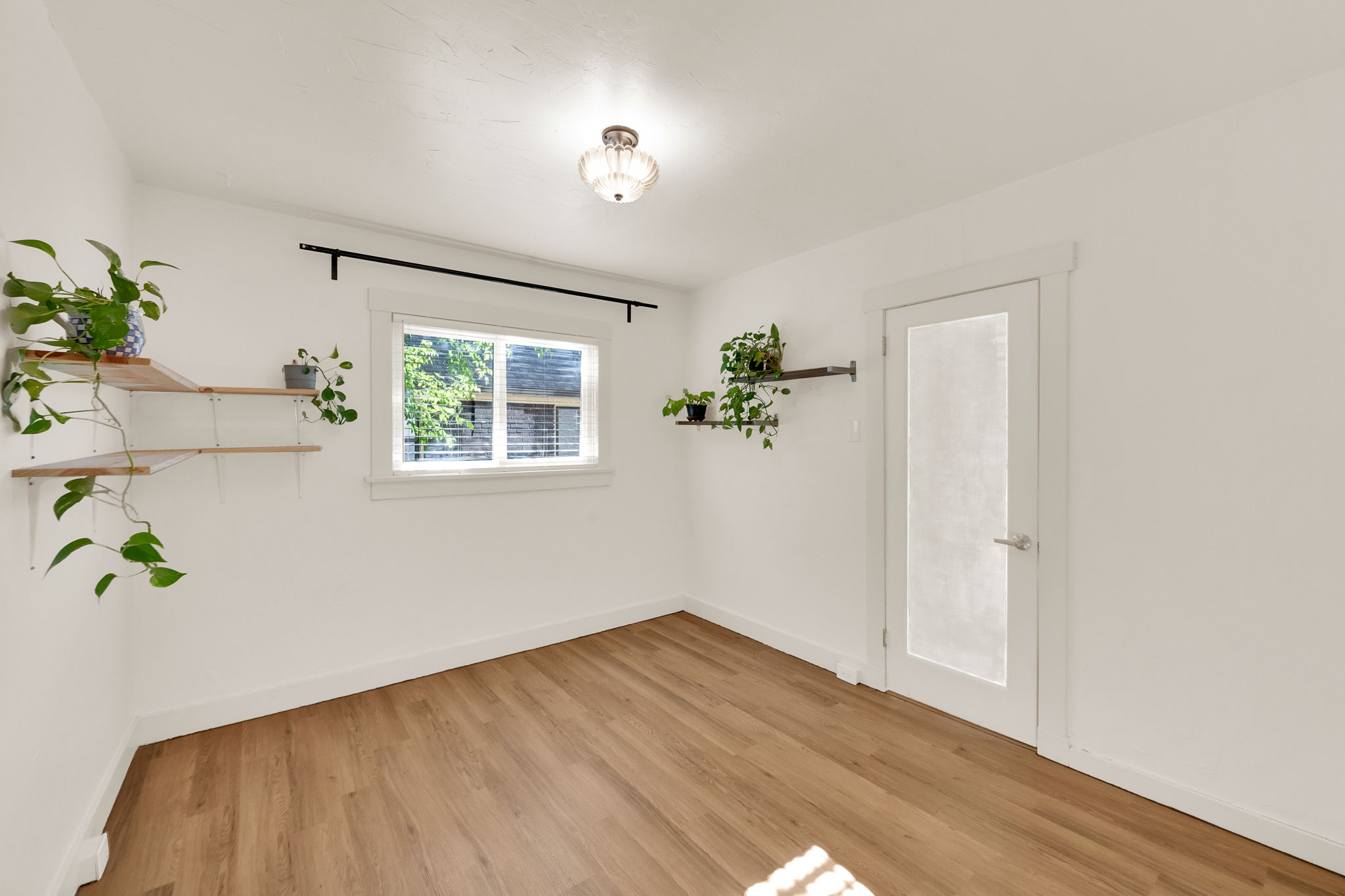 Room featuring wood-finish flooring, white walls, and a contemporary ceiling light fixture