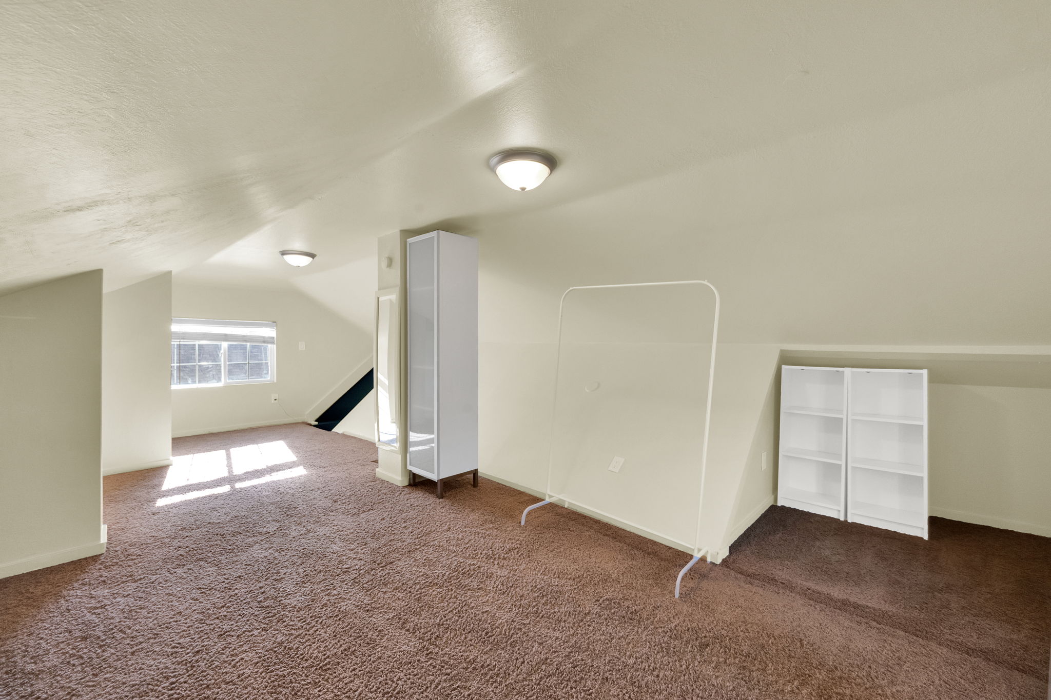 Carpeted attic space with sloped ceilings and recessed lighting