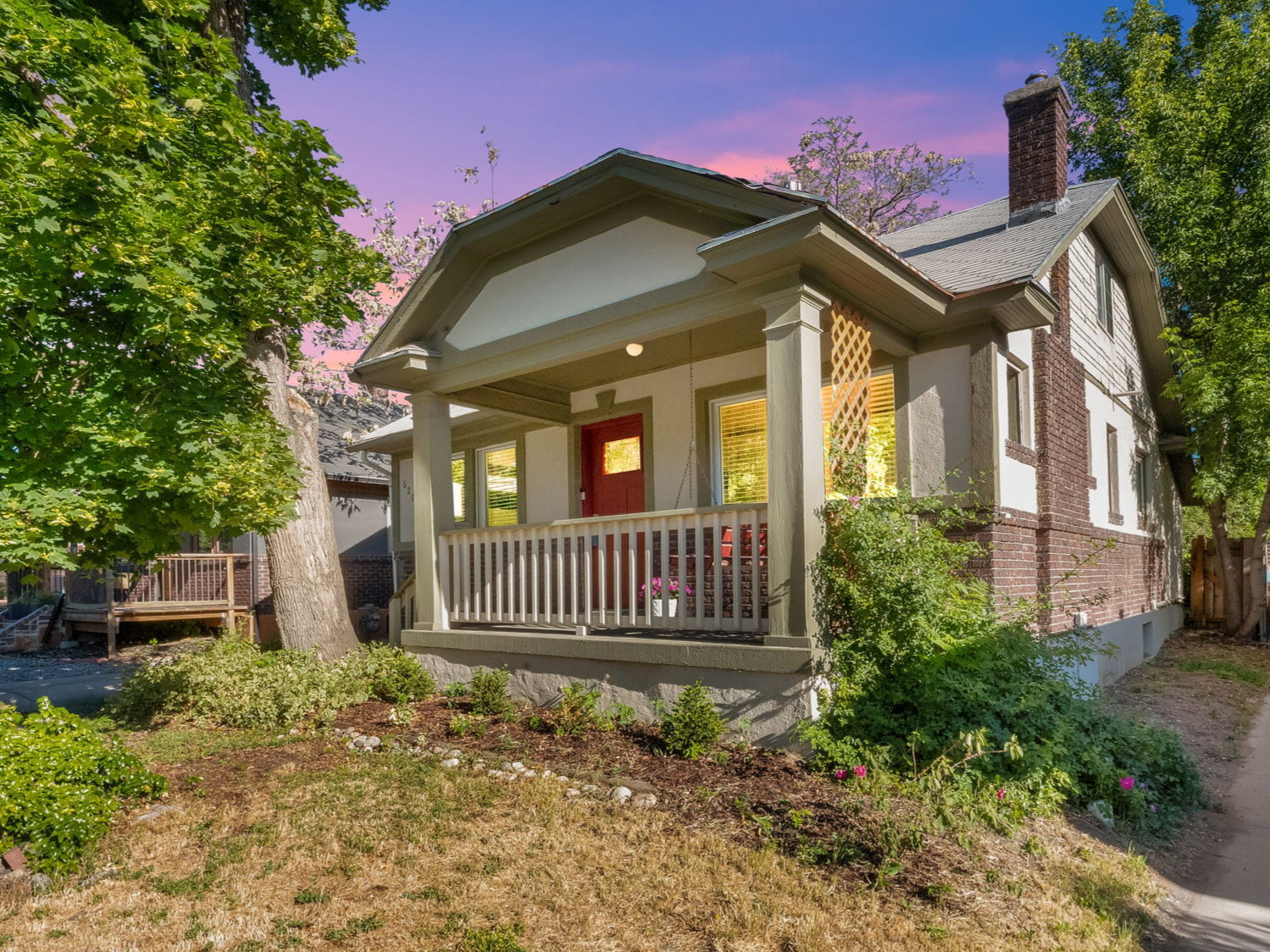 Craftsman-style home featuring a covered front porch with white railings, a red entry door, and a brick and siding exterior