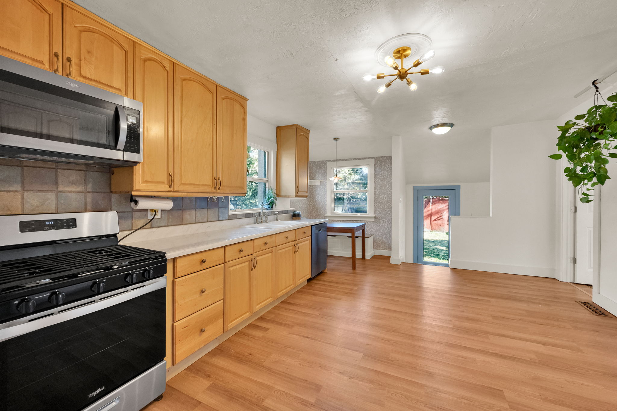 Kitchen featuring wood cabinetry, stainless steel appliances, laminate countertops, and a tiled backsplash