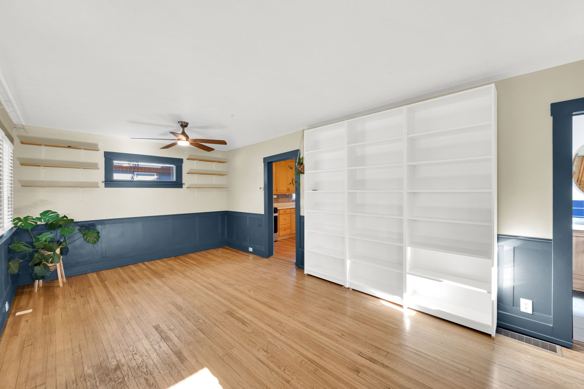 Hardwood flooring throughout a room featuring a full wall of built-in white shelving
