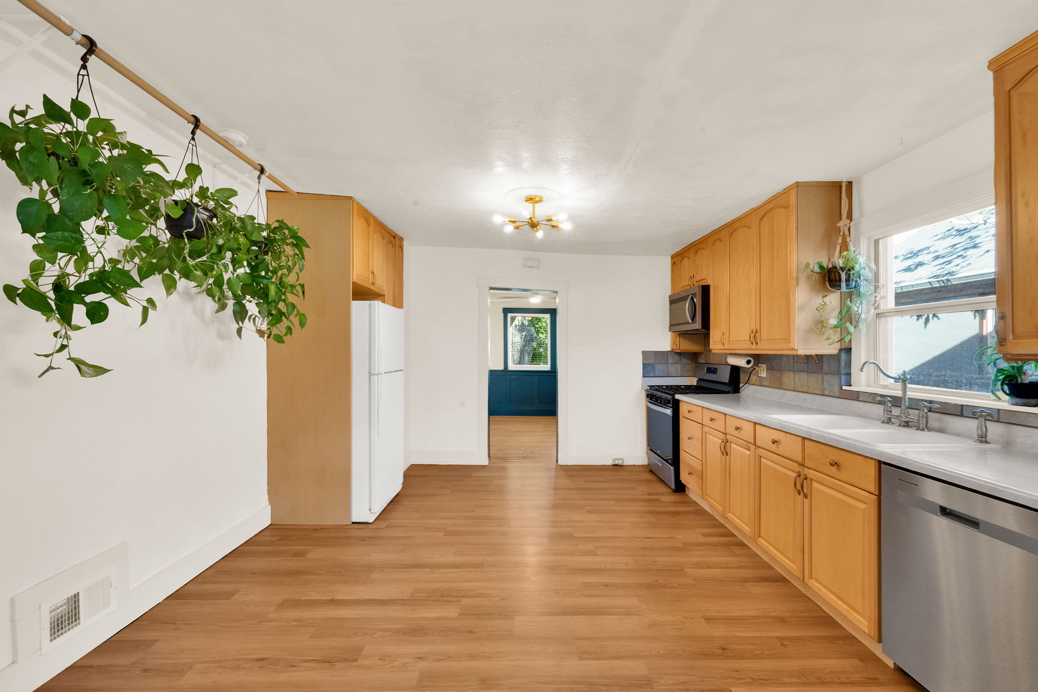 Kitchen featuring wood-finish flooring, ample wood cabinetry, a stainless steel dishwasher, and a stainless steel oven with microwave