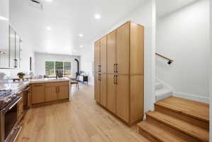 Open-concept living space featuring wood-finish flooring, recessed lighting, and a modern kitchen with light wood cabinetry and stainless steel appliances