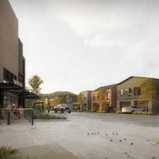 Modern mixed-use streetscape featuring a ground-floor commercial space with outdoor seating, contemporary residential townhomes with attached garages, and paved sidewalks