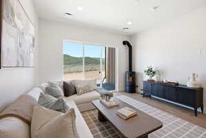 Living area with a freestanding wood-burning stove, large sliding glass doors, recessed lighting, and wood-finish flooring