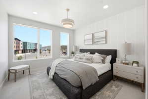 Recessed lighting and a contemporary chandelier illuminate this space featuring a large window and a vertical accent wall