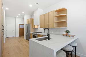 Modern kitchen featuring a waterfall island with a built-in sink and matte black faucet