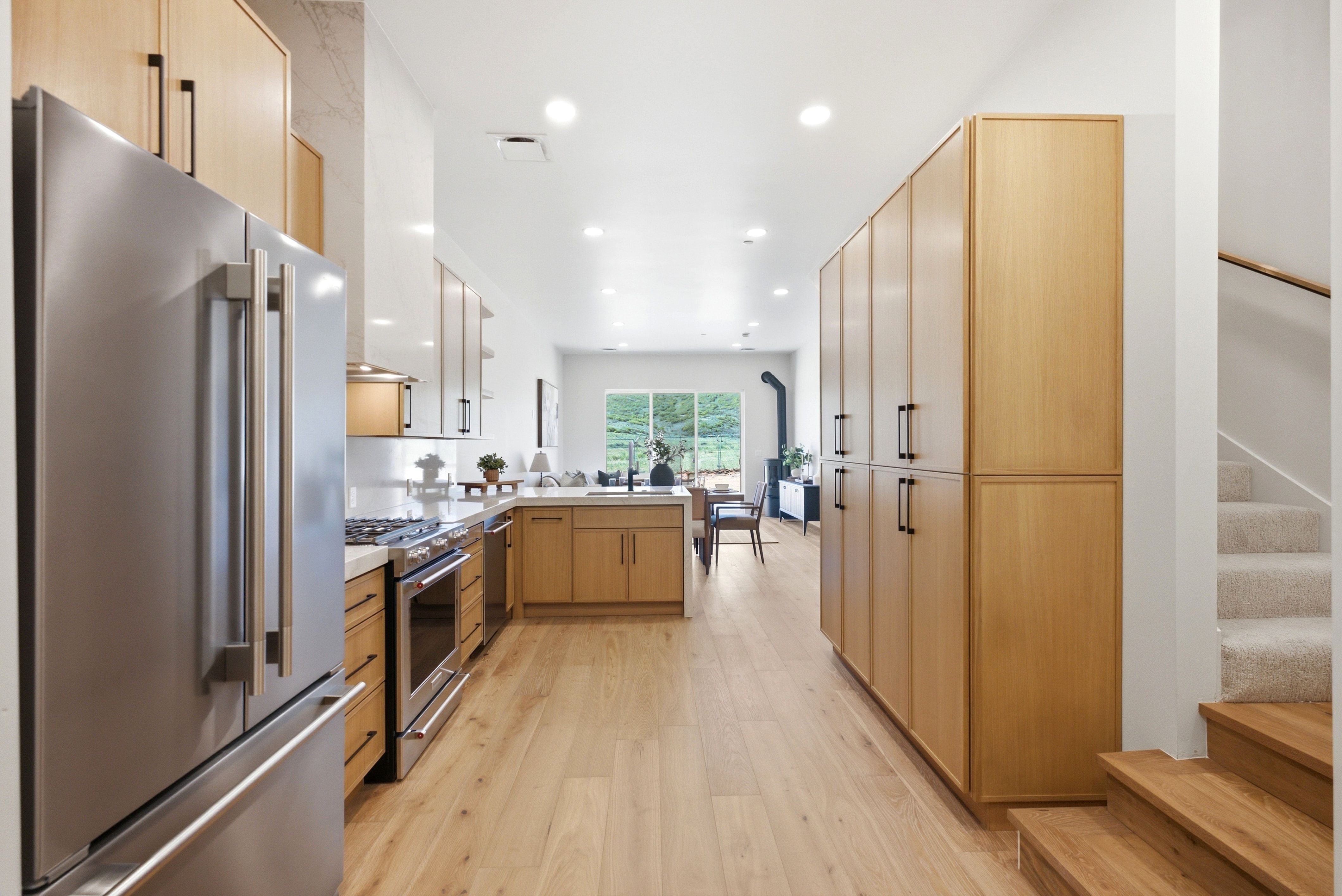 Open-concept kitchen featuring light wood-finish cabinetry, stainless steel appliances, light wood-finish flooring, and recessed lighting