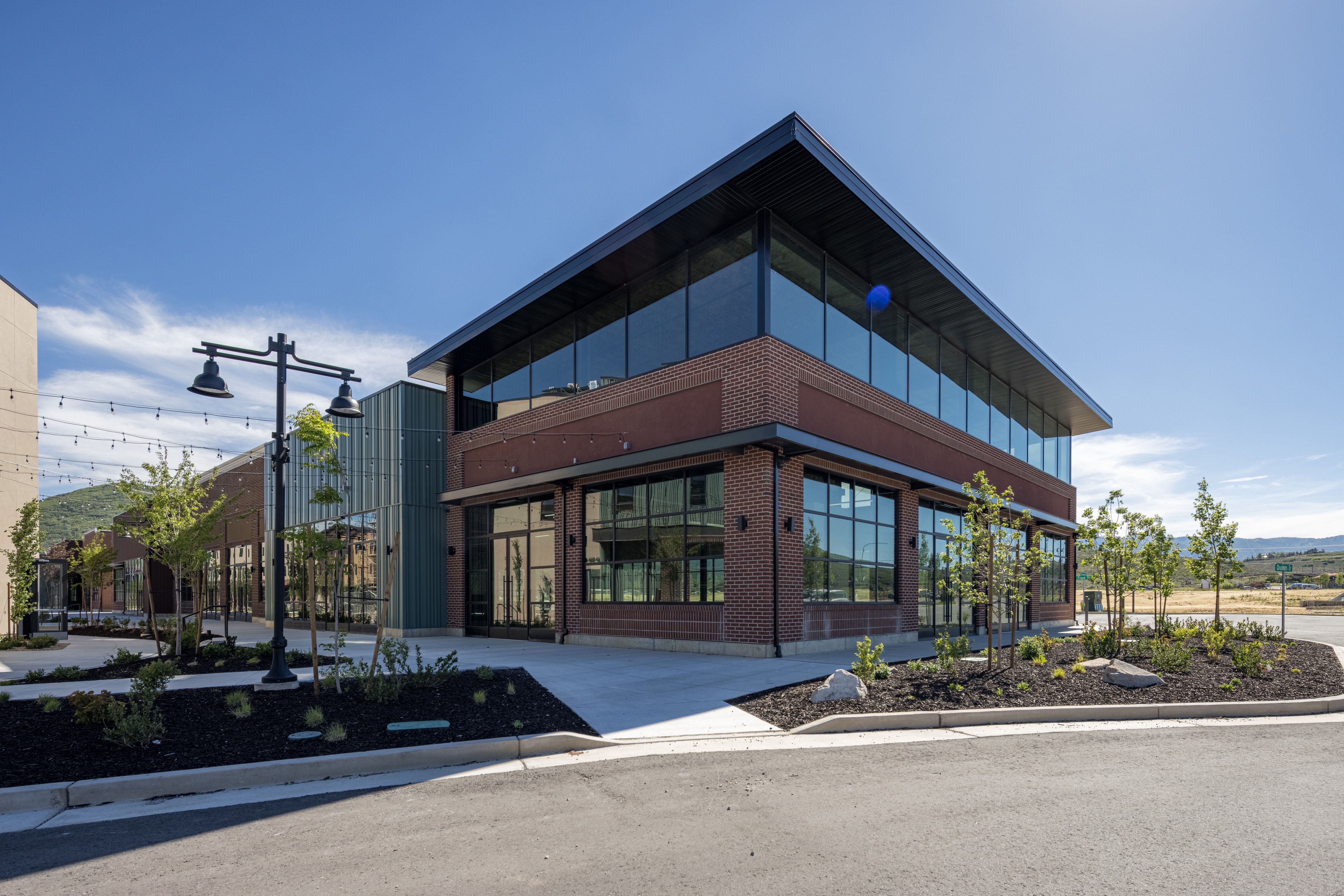 Modern commercial building featuring extensive glazing, brick facade, and a dark overhanging roof