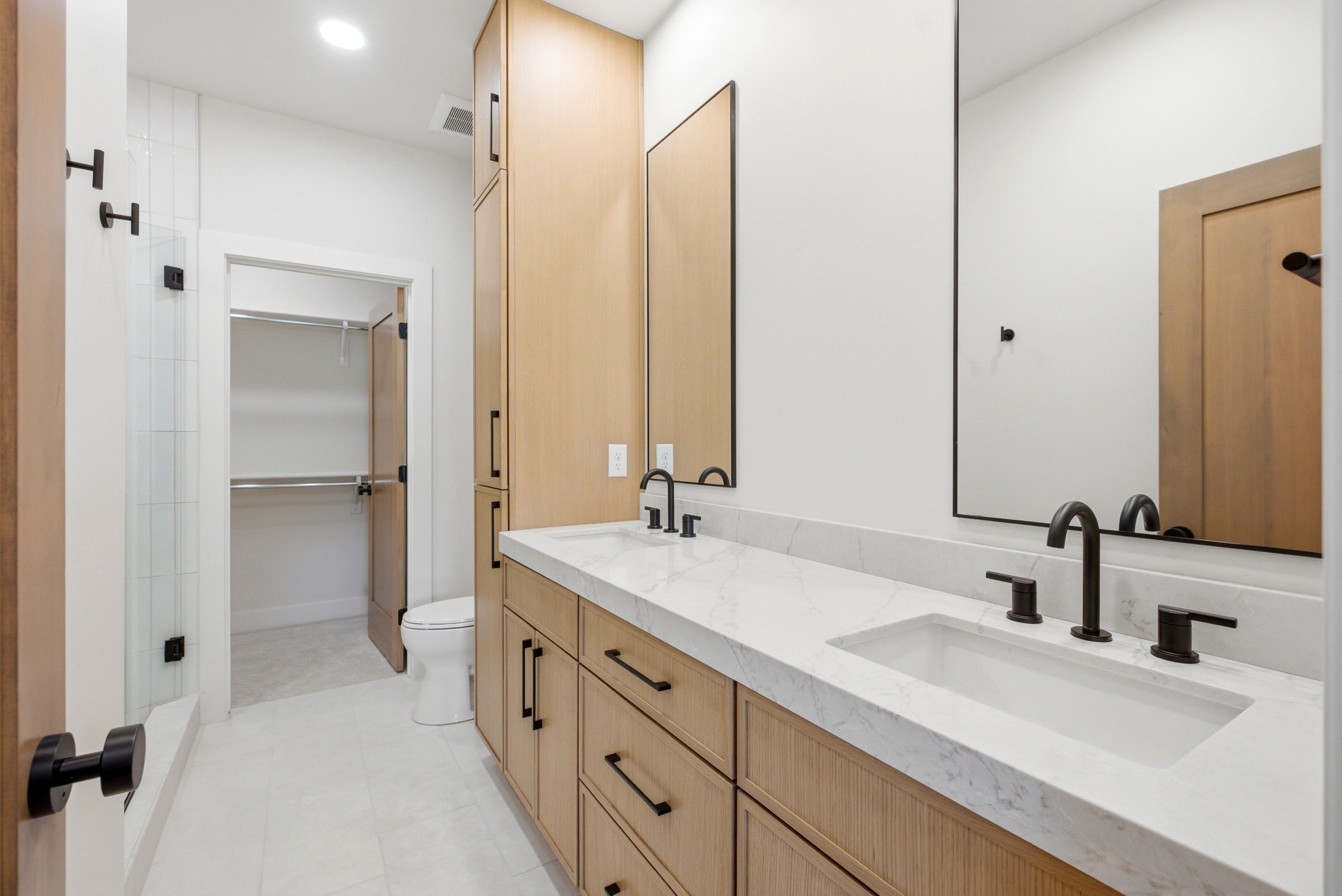 Dual vanity featuring undermount sinks, stone countertops, and matte black fixtures