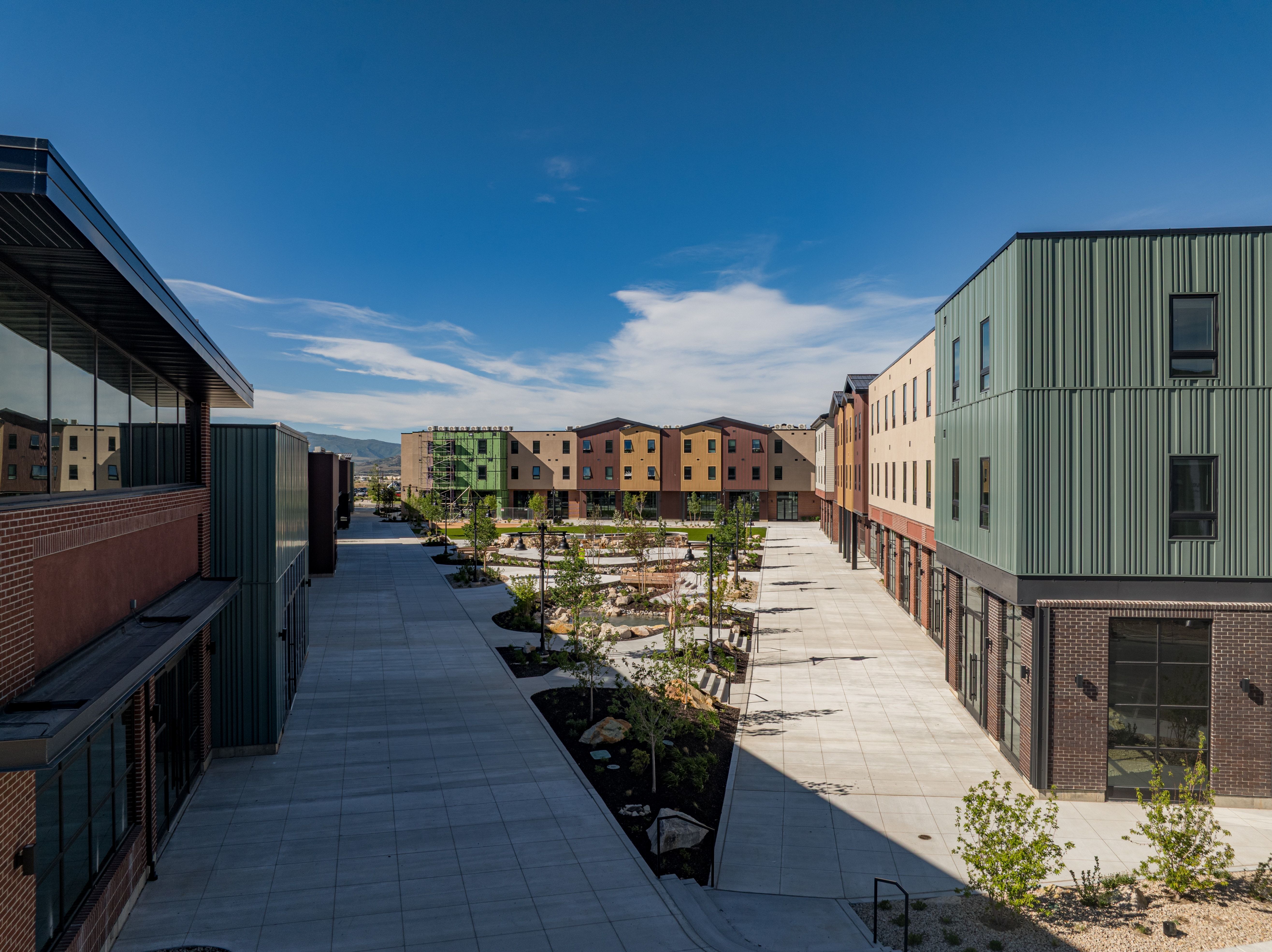 Modern multi-story buildings featuring brick and vertical panel siding in varied colors