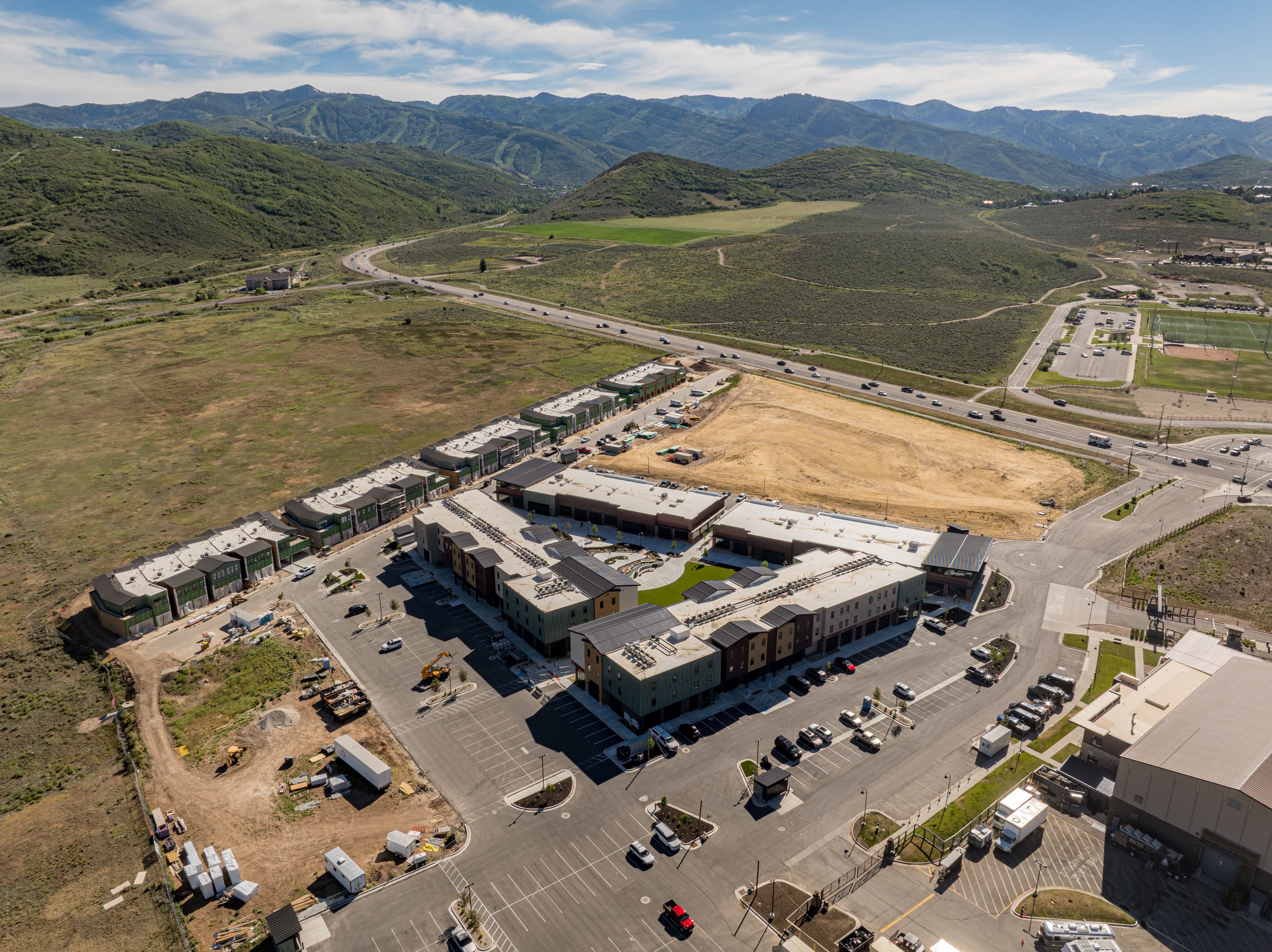 Modern multi-building development featuring varied architectural styles and ample surface parking