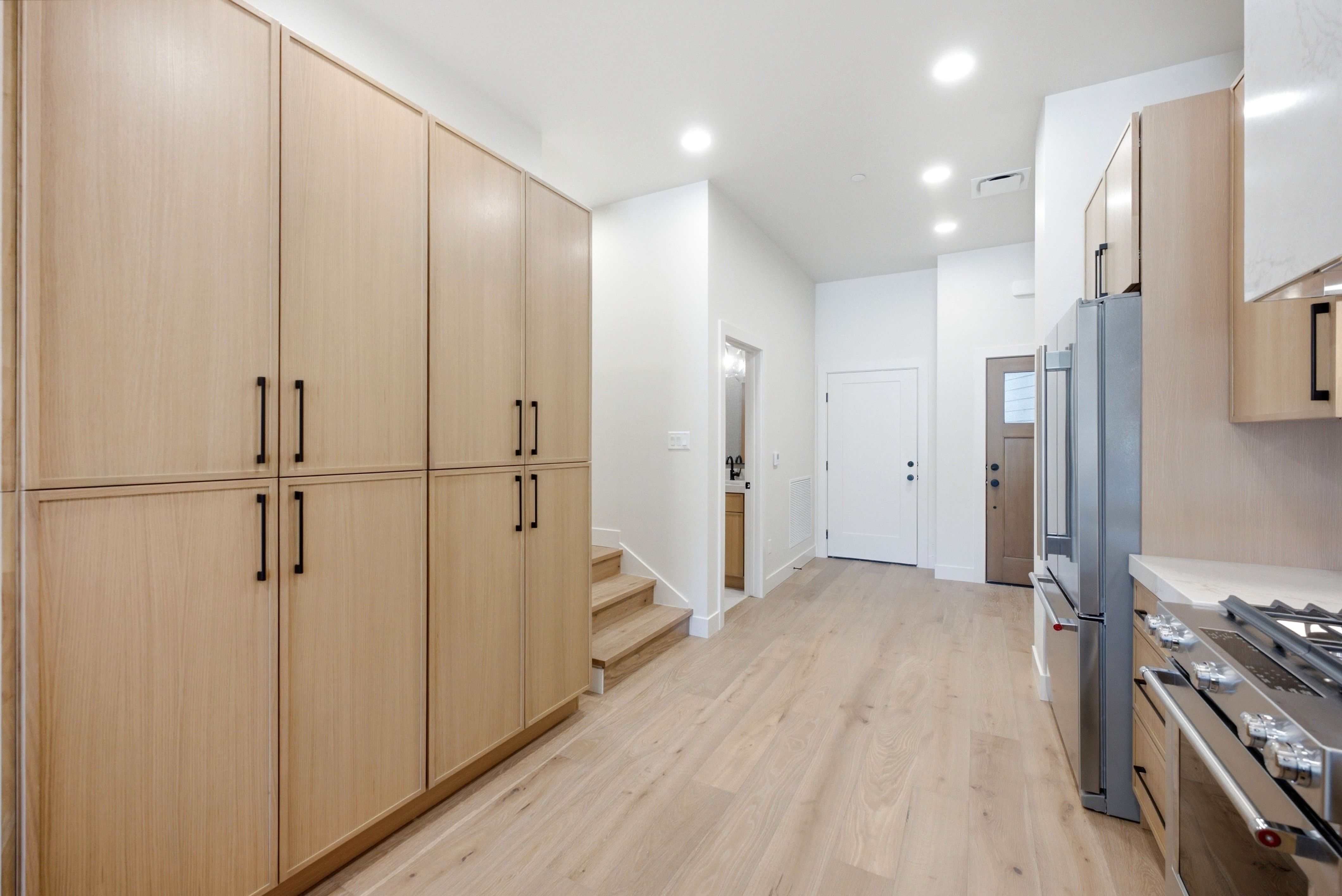 Integrated light wood-finish cabinetry with matte black hardware
