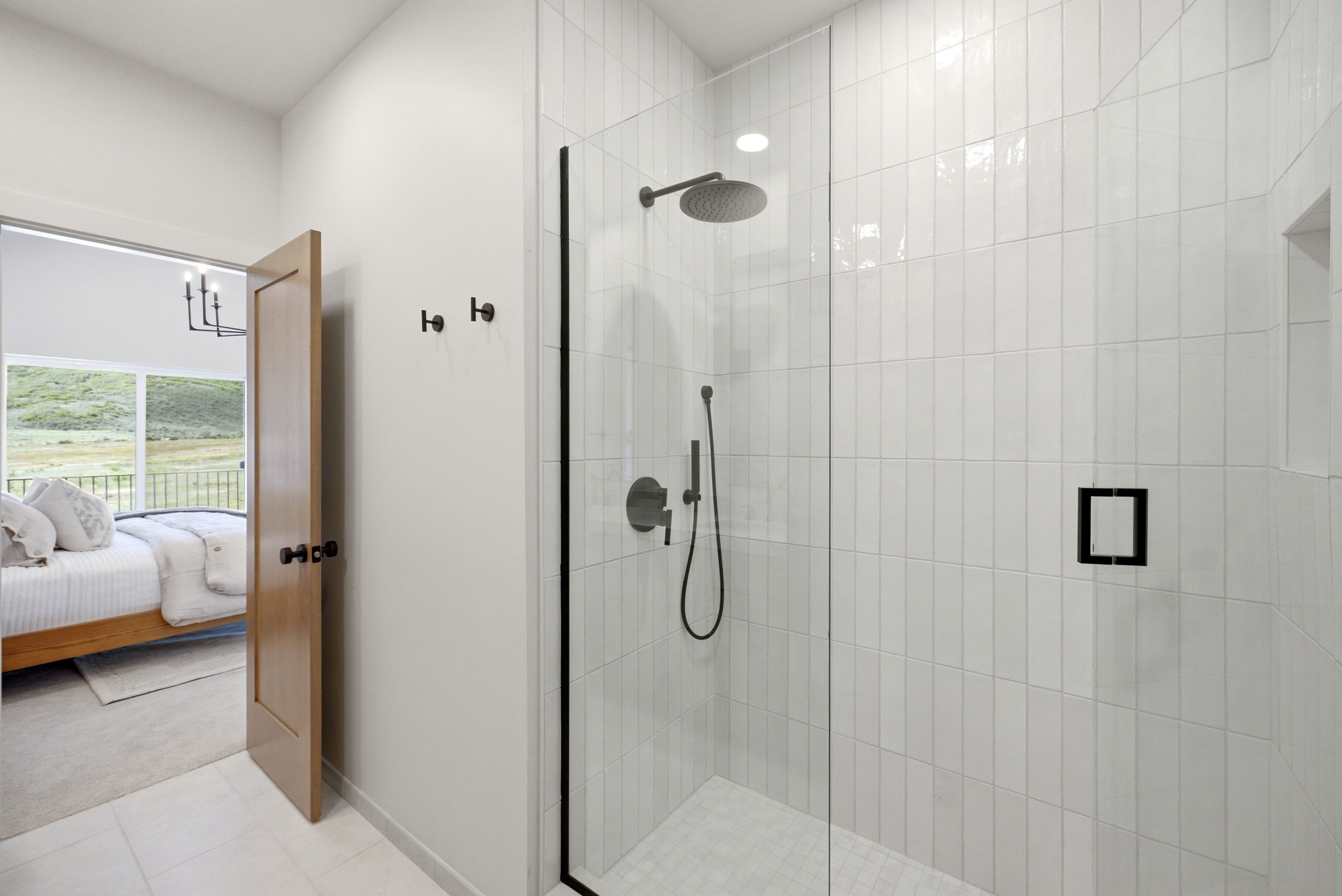 Walk-in shower featuring vertical subway tile, a dark-framed glass enclosure, and matte black fixtures