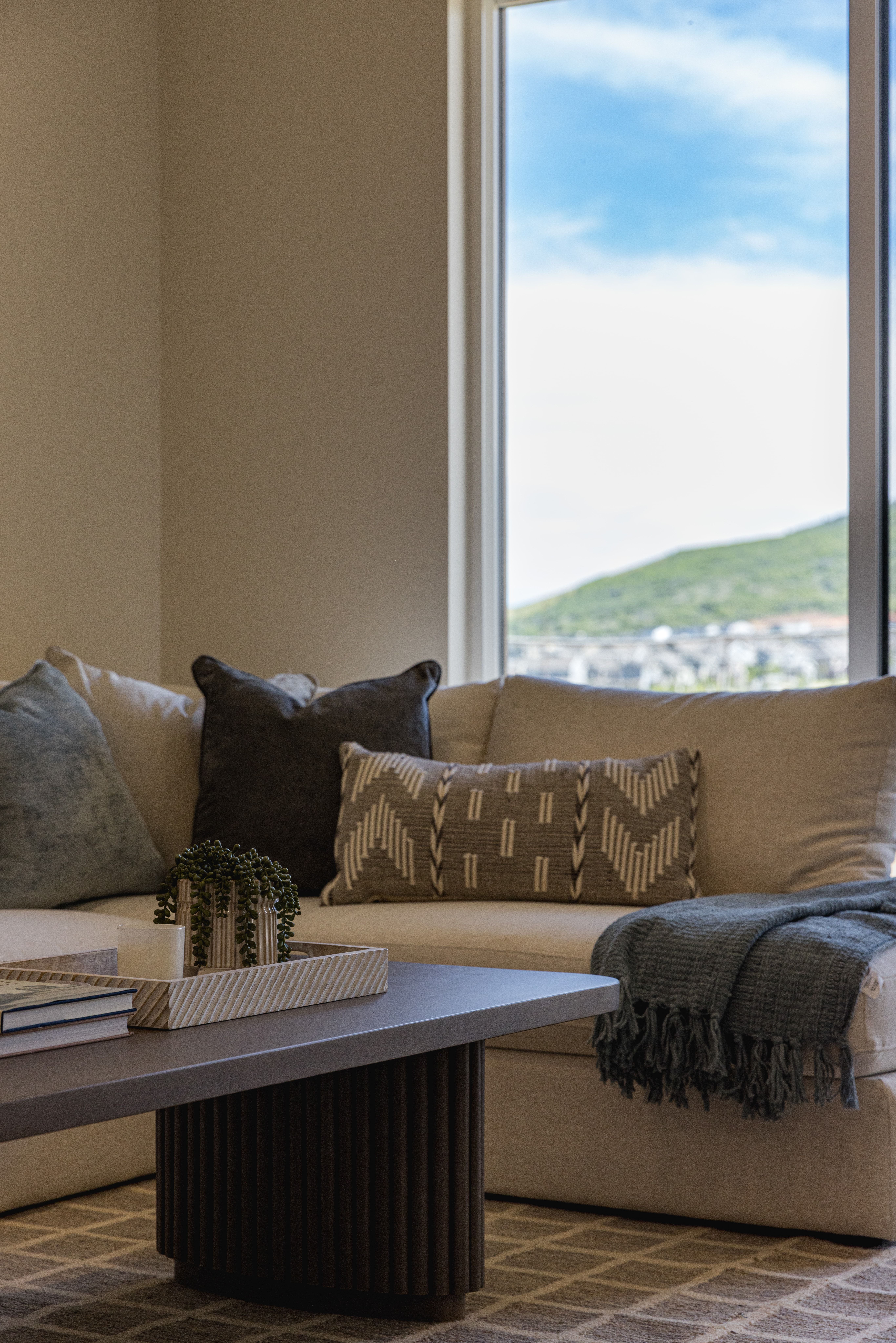 Bright interior with large windows, neutral wall tones, and a geometric patterned area rug