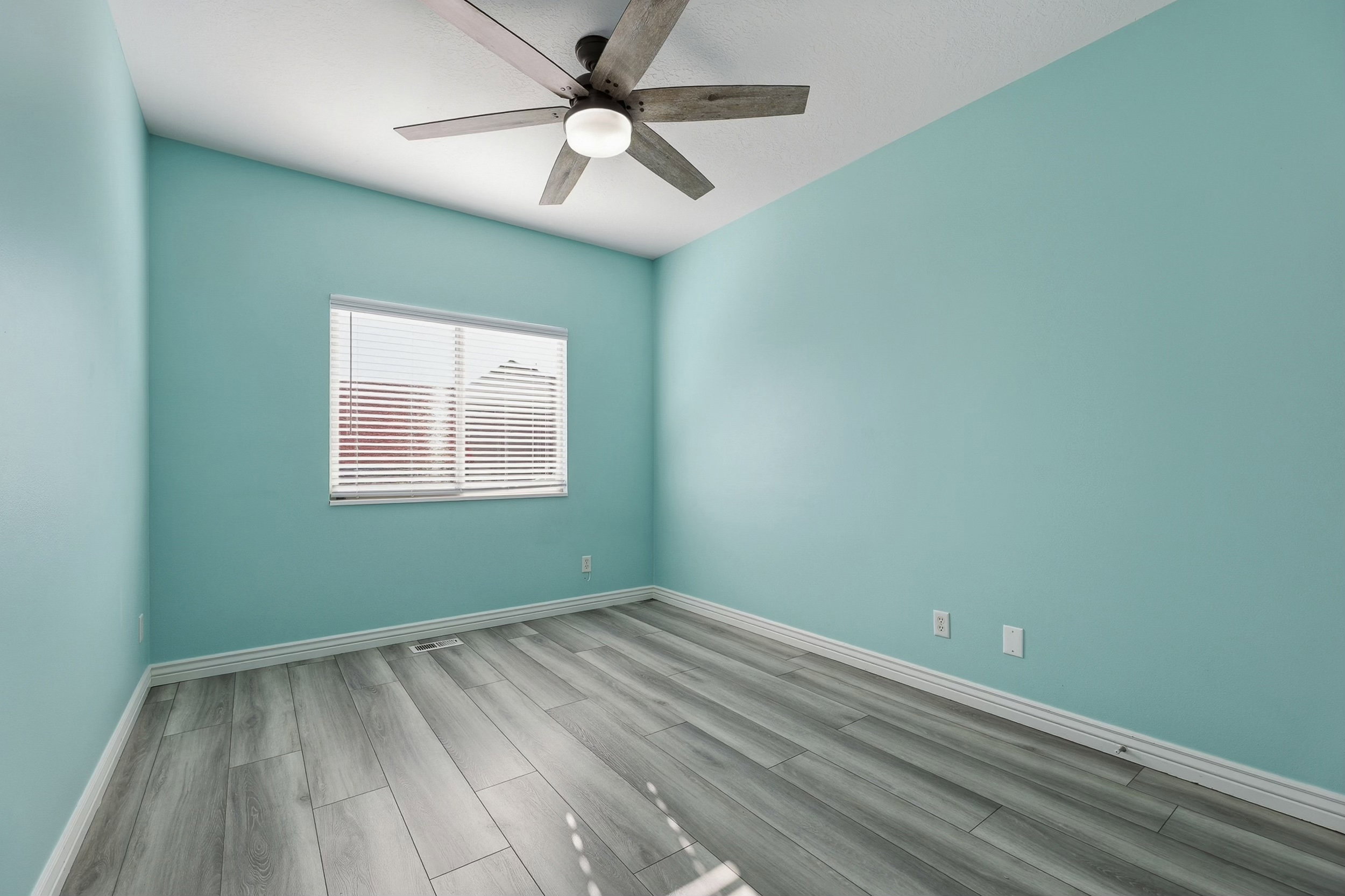 Room featuring wood-finish flooring, a ceiling fan with light fixture, and a window with horizontal blinds