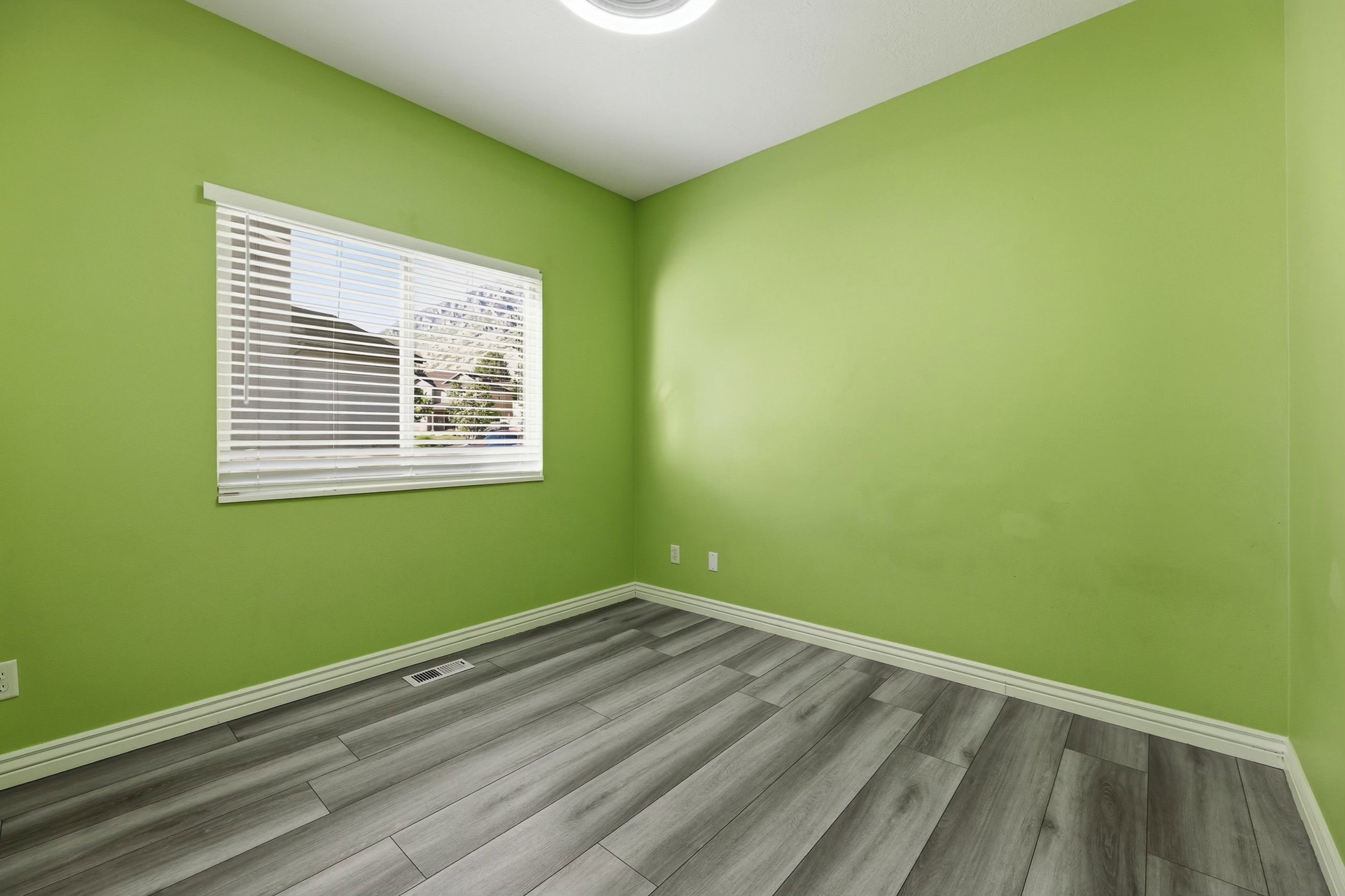 Room featuring wood-finish flooring, white baseboards, and a window with blinds