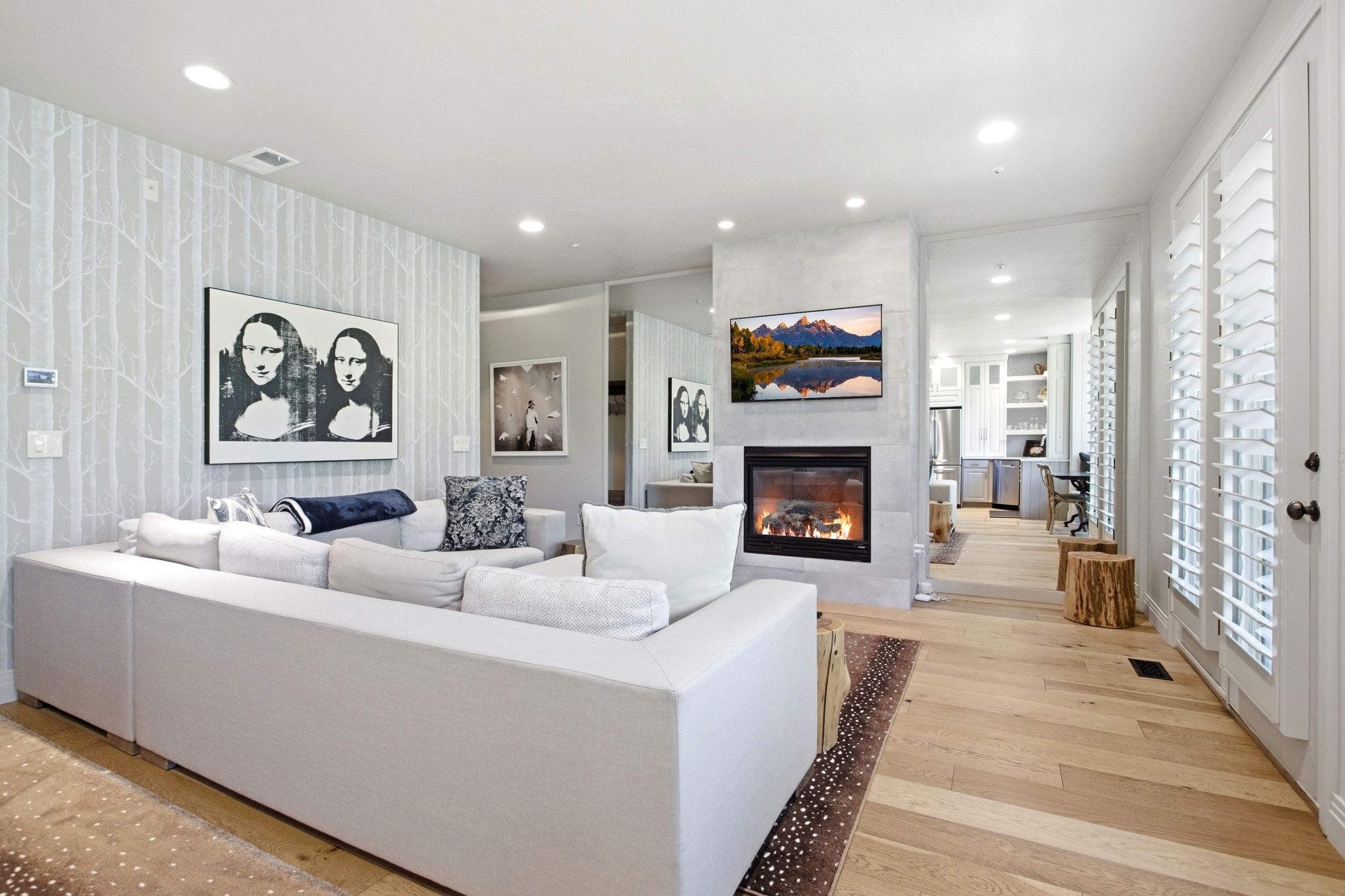 Living area featuring wood-finish flooring, recessed lighting, and a modern fireplace with a light-toned surround