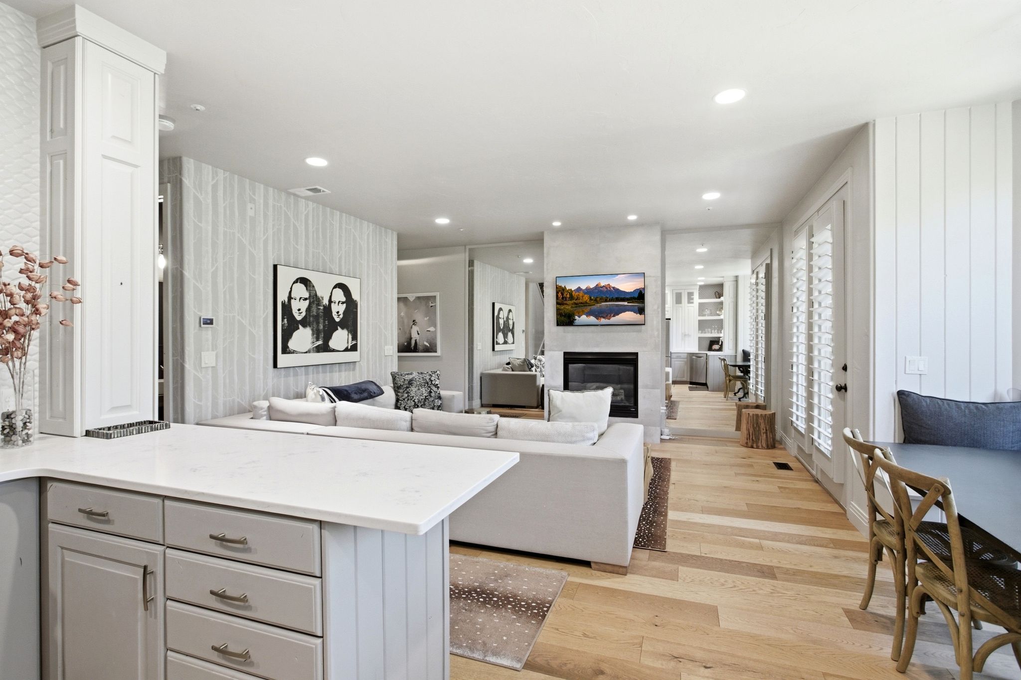 Open-concept living area featuring light wood-finish flooring, a contemporary fireplace with a mounted television, and recessed ceiling lighting