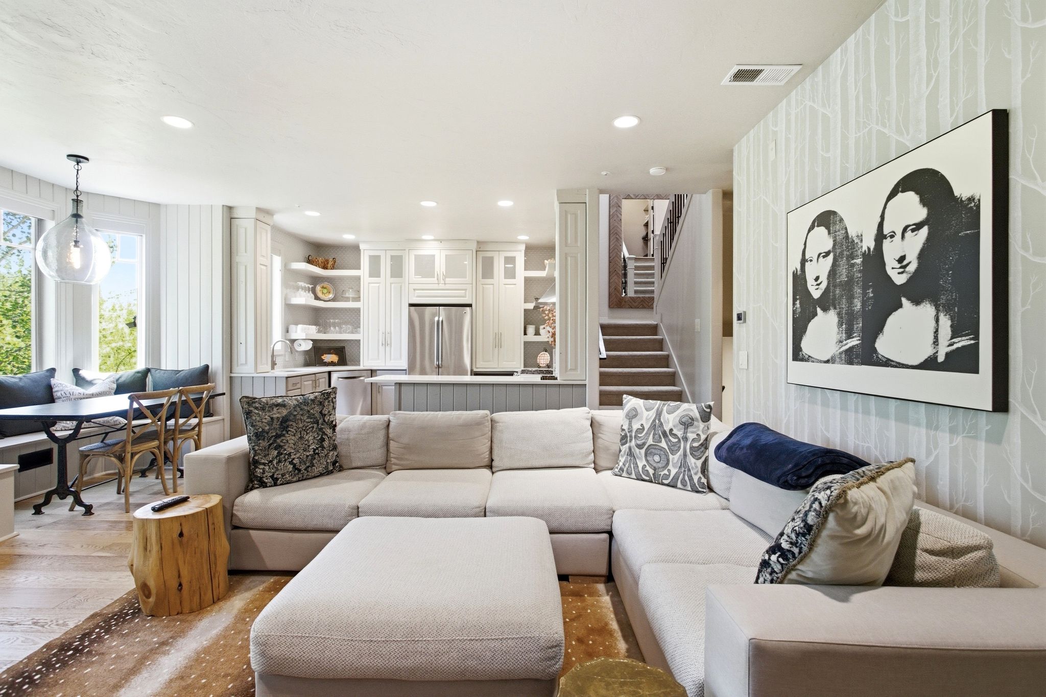 Open-concept living area featuring wood-finish flooring, recessed lighting, and a built-in banquette dining space with large windows