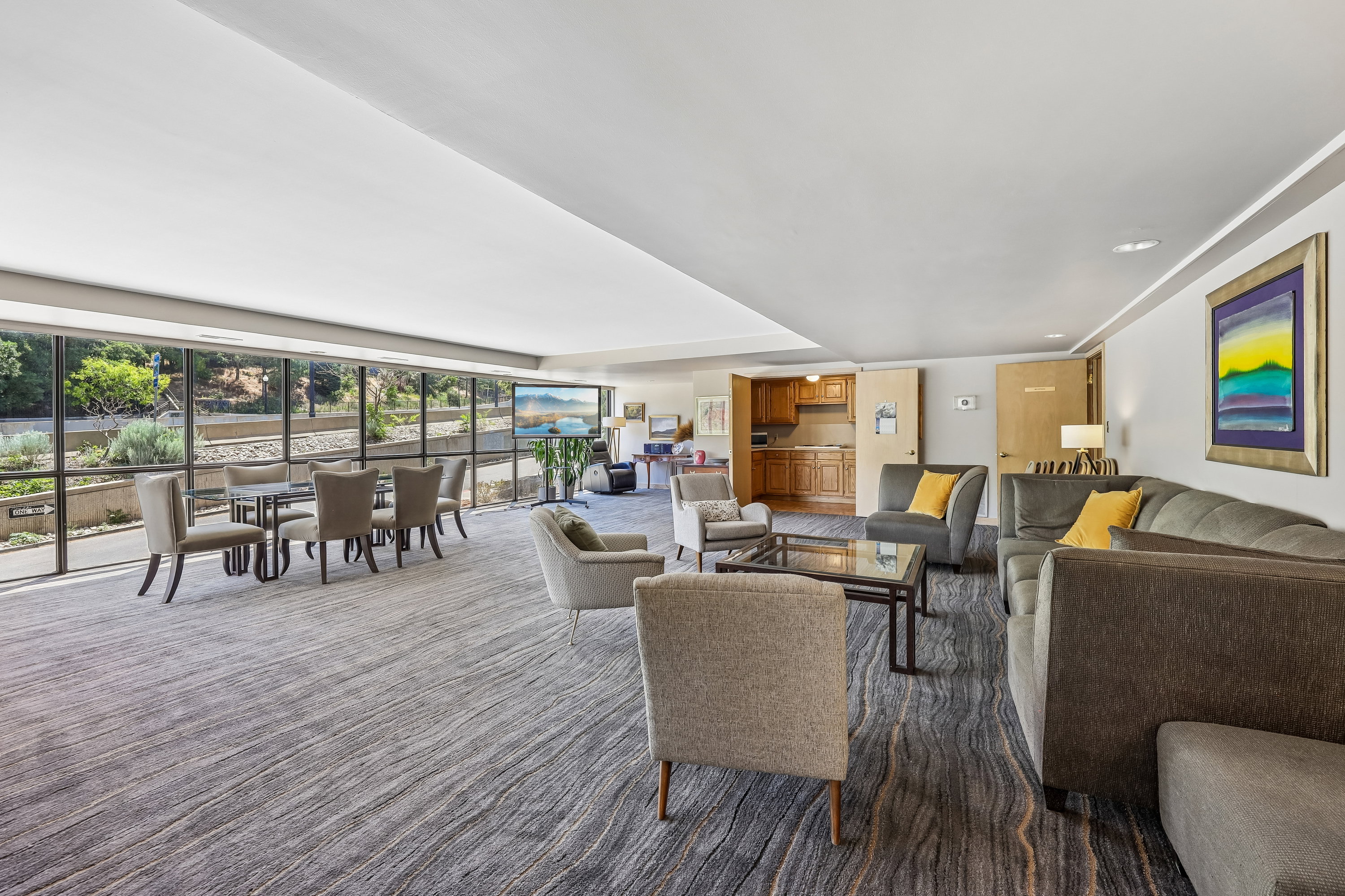 Spacious common area featuring full-height windows, patterned carpet flooring, and recessed ceiling lighting