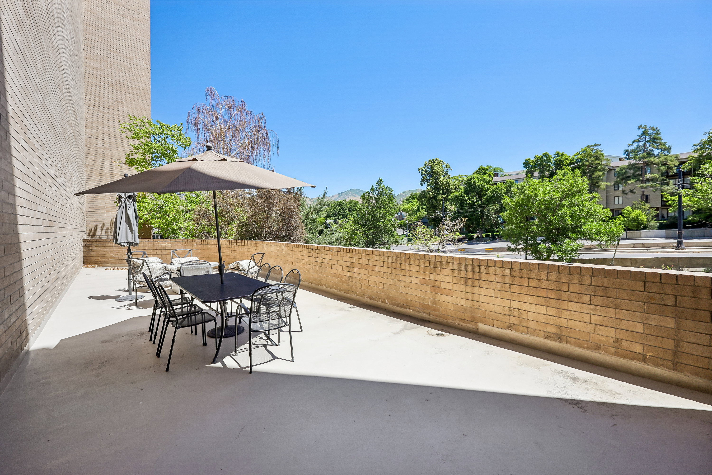 Spacious outdoor patio with a concrete surface and a partial brick privacy wall