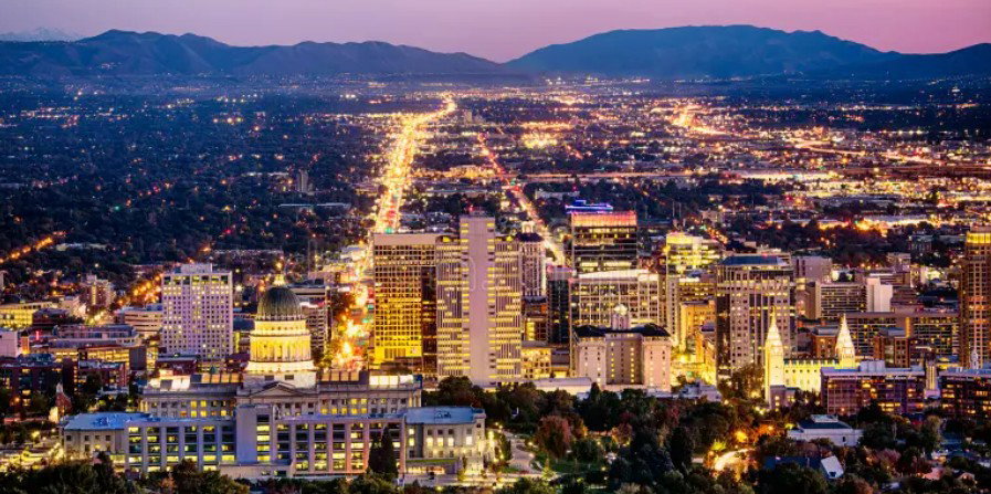 Expansive cityscape at twilight featuring numerous illuminated buildings and a prominent domed structure