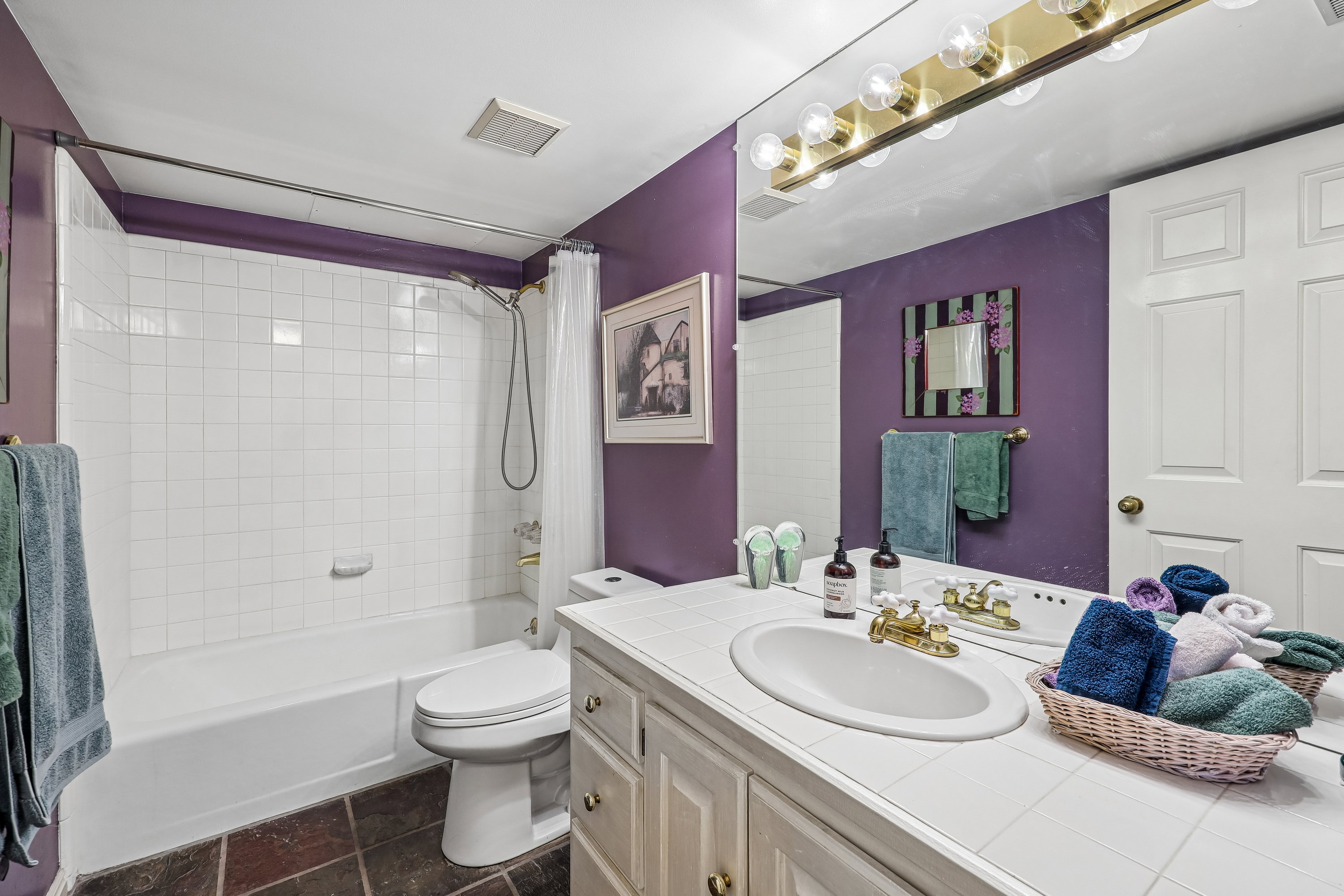 Bathroom vanity featuring an oval undermount sink with a gold-tone faucet, set into a white tile countertop