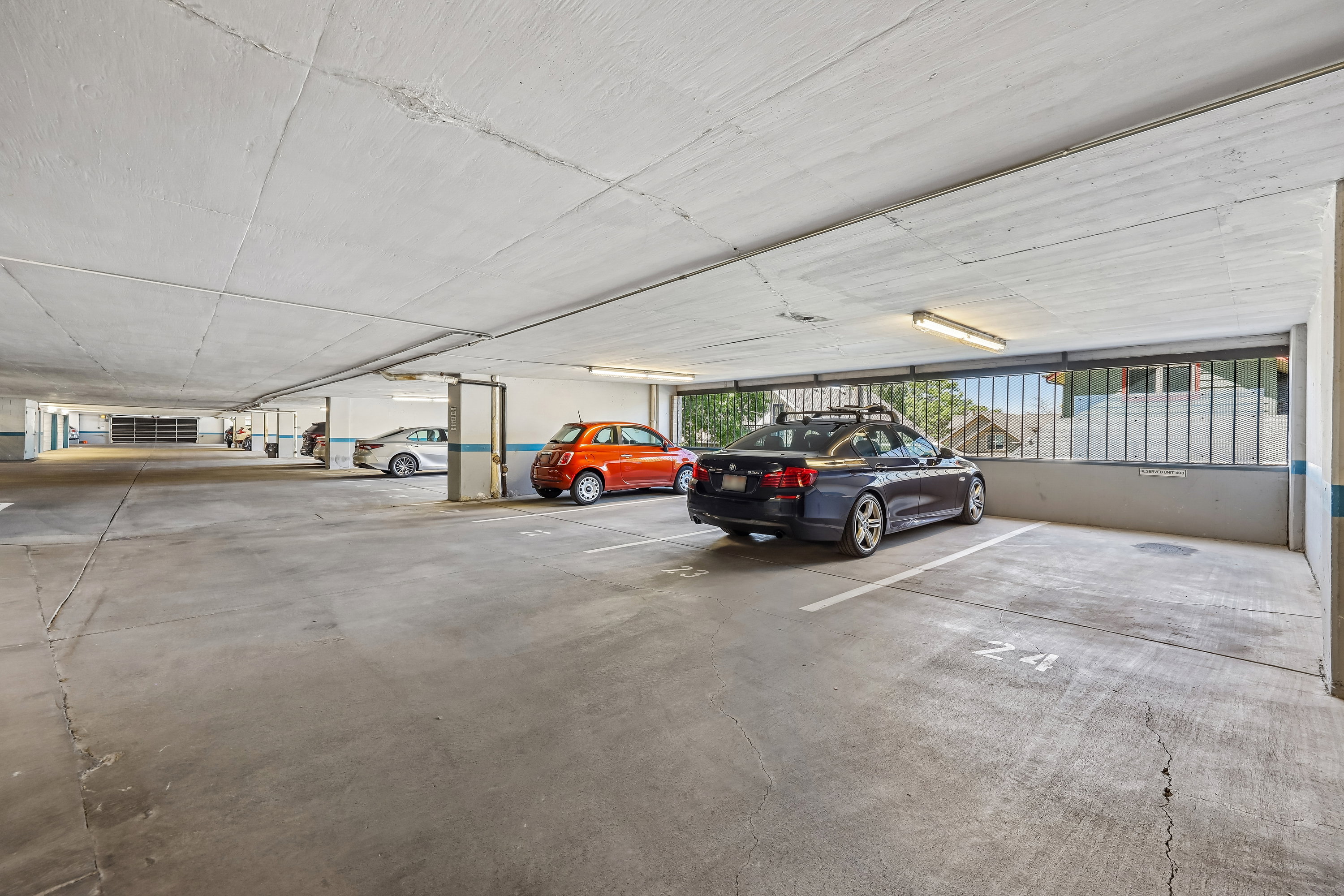 Covered parking garage featuring concrete flooring, structural columns, and integrated lighting