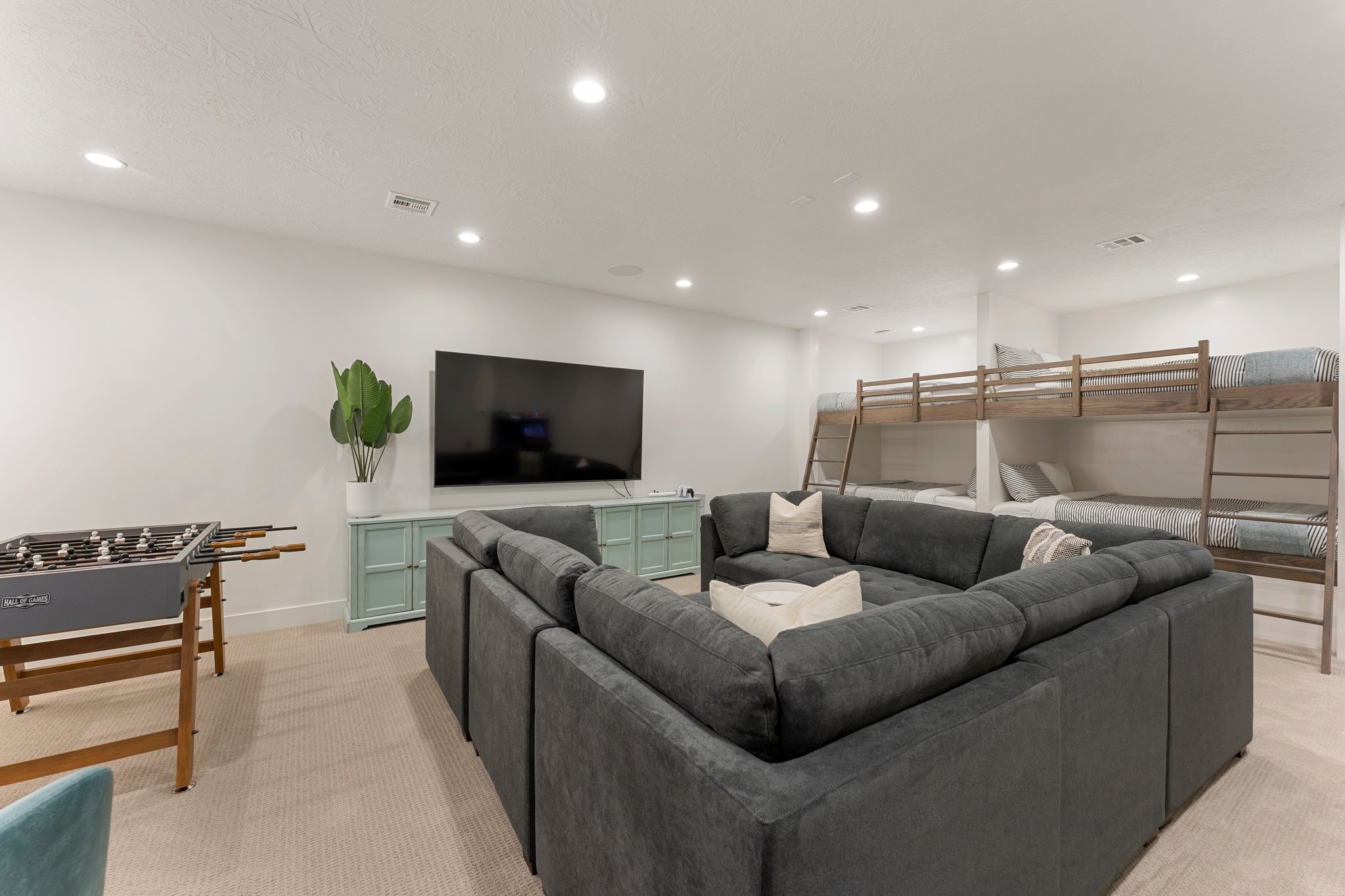 Spacious recreation room featuring recessed lighting, light-colored carpeting, a built-in entertainment console, and integrated bunk beds