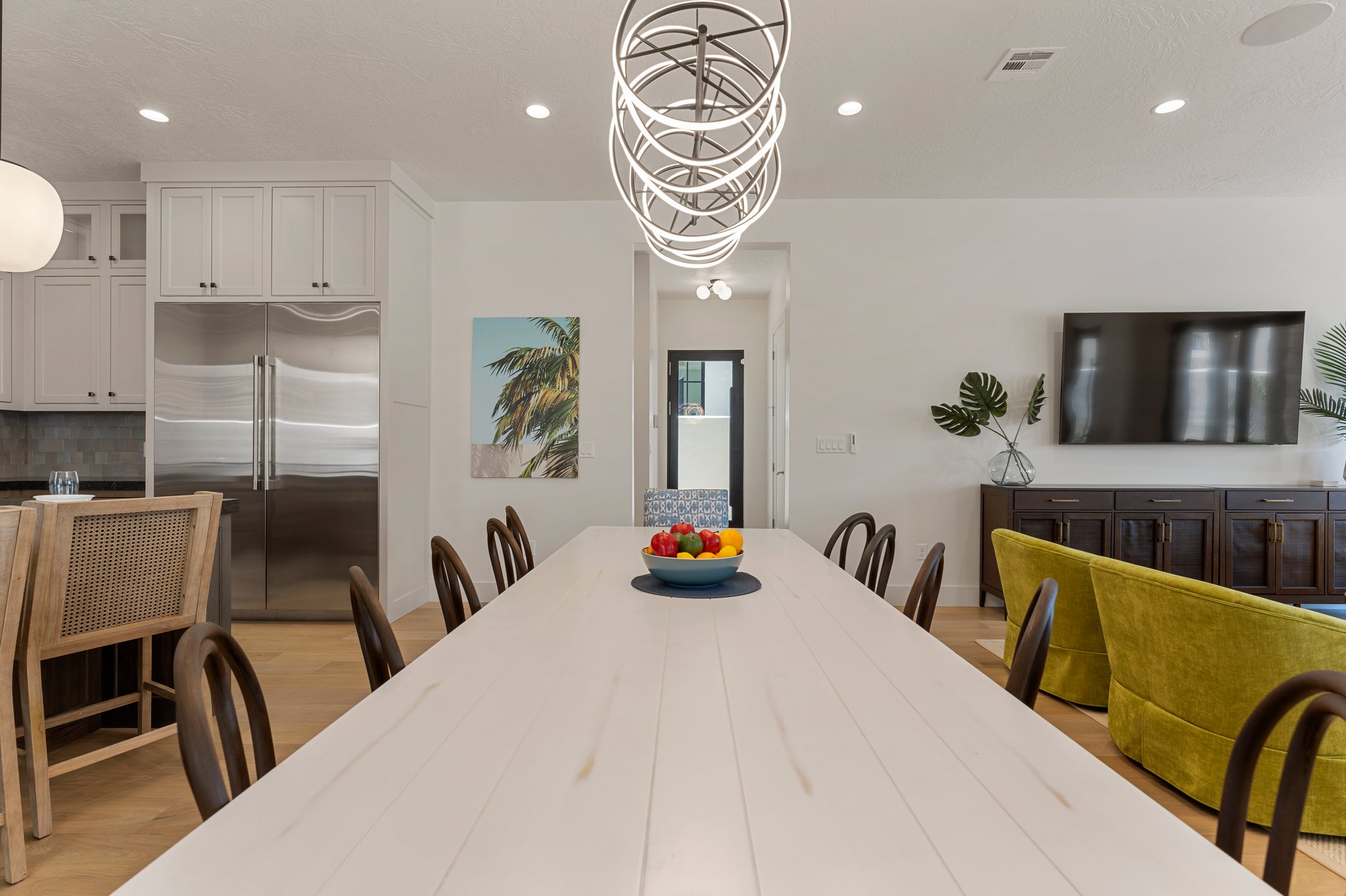 Open-concept living space featuring a long dining table with wood-finish flooring