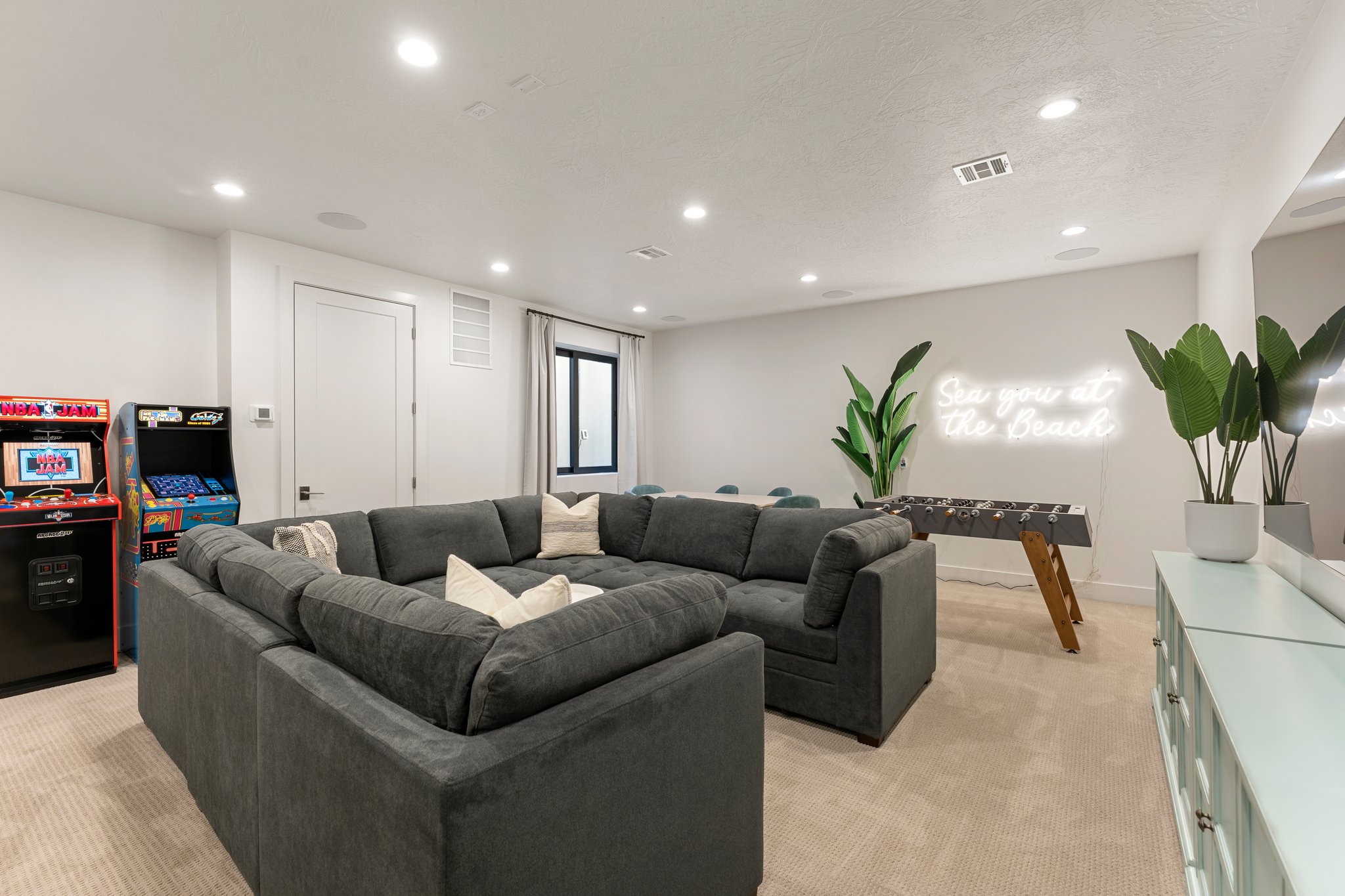 Spacious recreation room featuring recessed lighting, light-toned carpeting, and a built-in wall niche with an accent mirror
