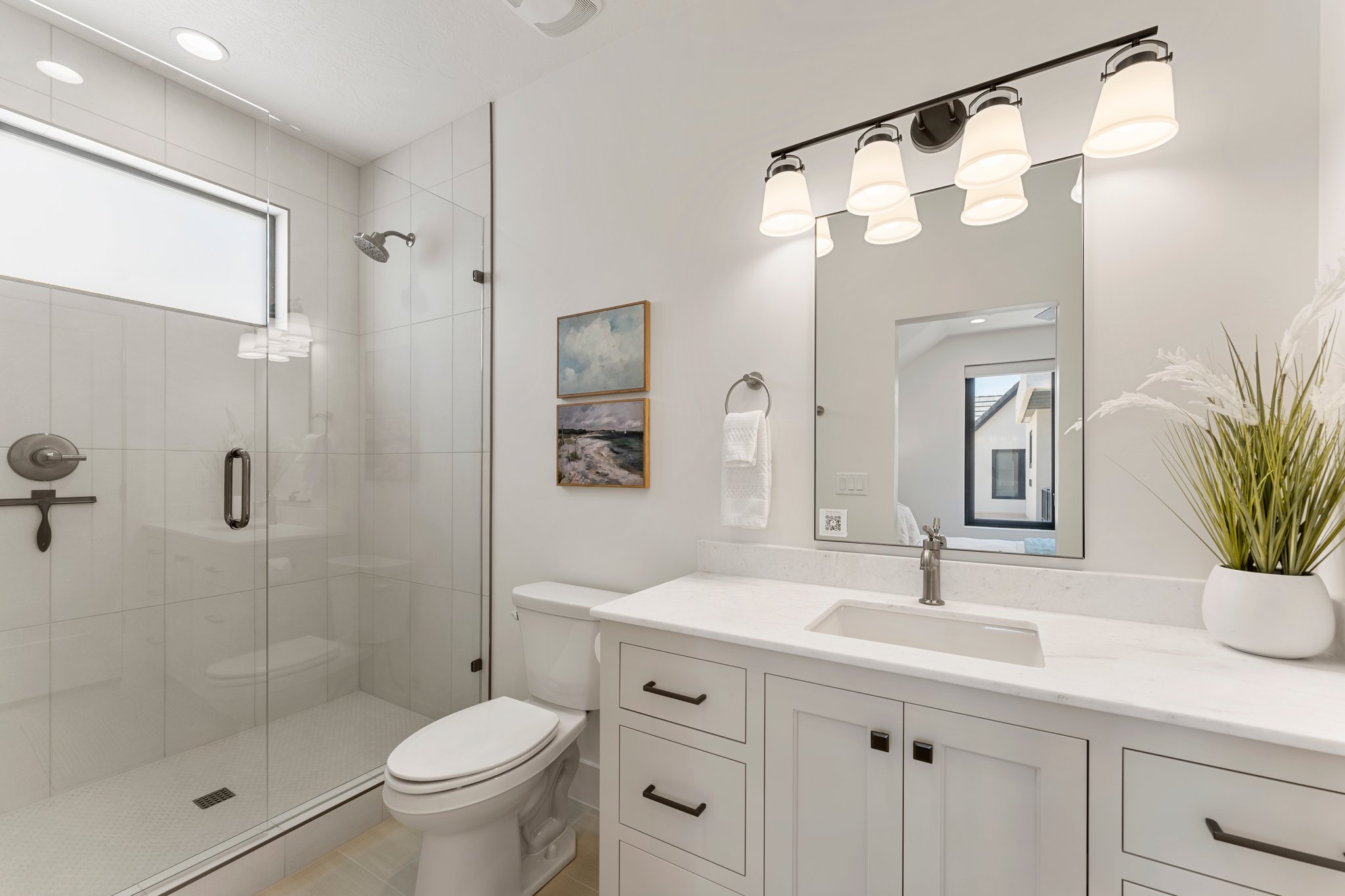 Modern bathroom featuring a glass-enclosed shower with subway tile surround and a transom window