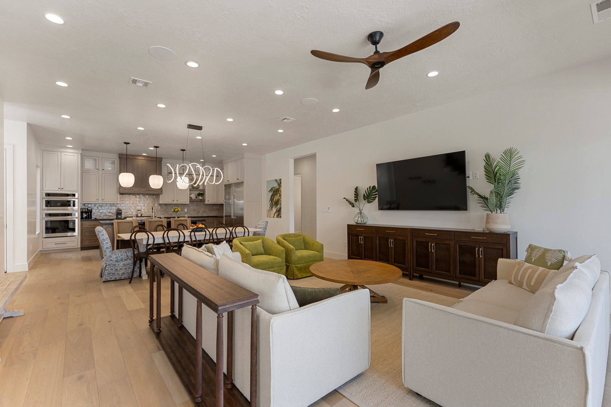 Open-concept living area with light wood-finish flooring, recessed lighting, and a modern ceiling fan