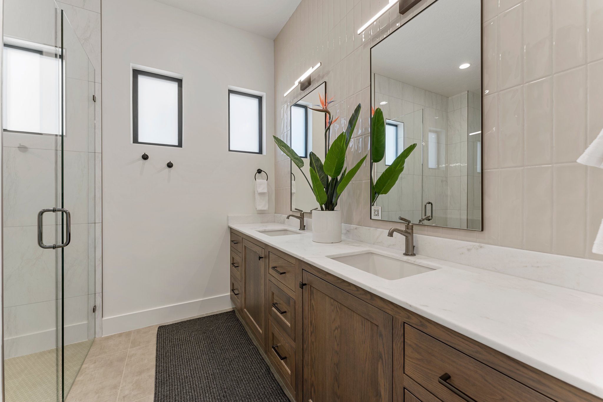 Double vanity featuring wood-finish cabinetry and integrated rectangular sinks with bronze-finish fixtures