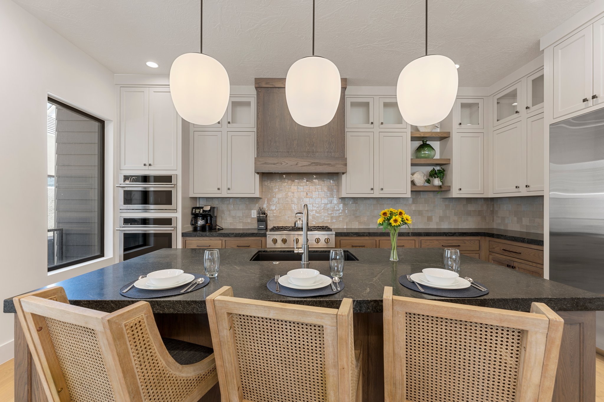 Kitchen island featuring a dark countertop, undermount sink, and three pendant lights