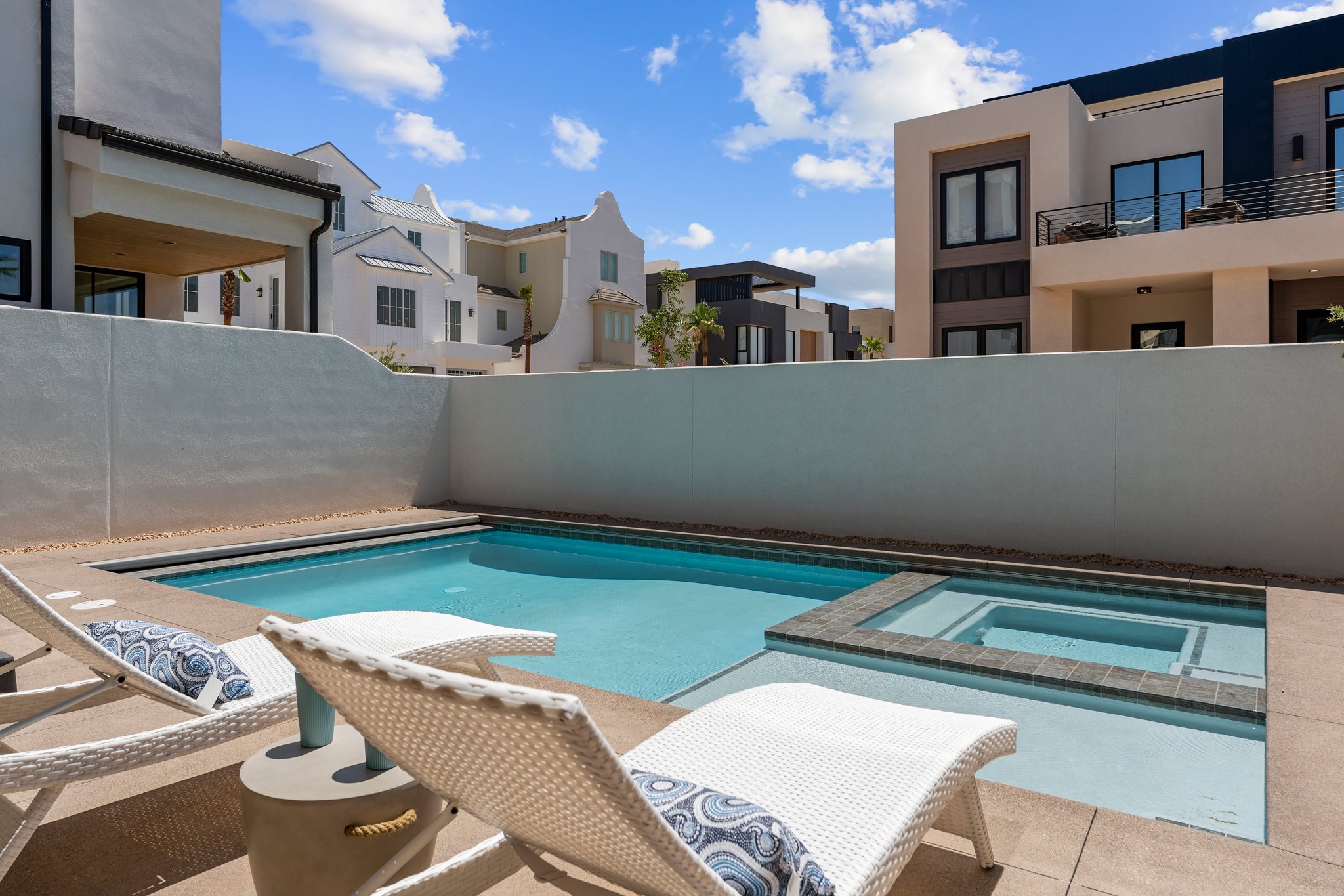 Private outdoor area featuring a swimming pool with an integrated spa, surrounded by concrete decking and a perimeter wall