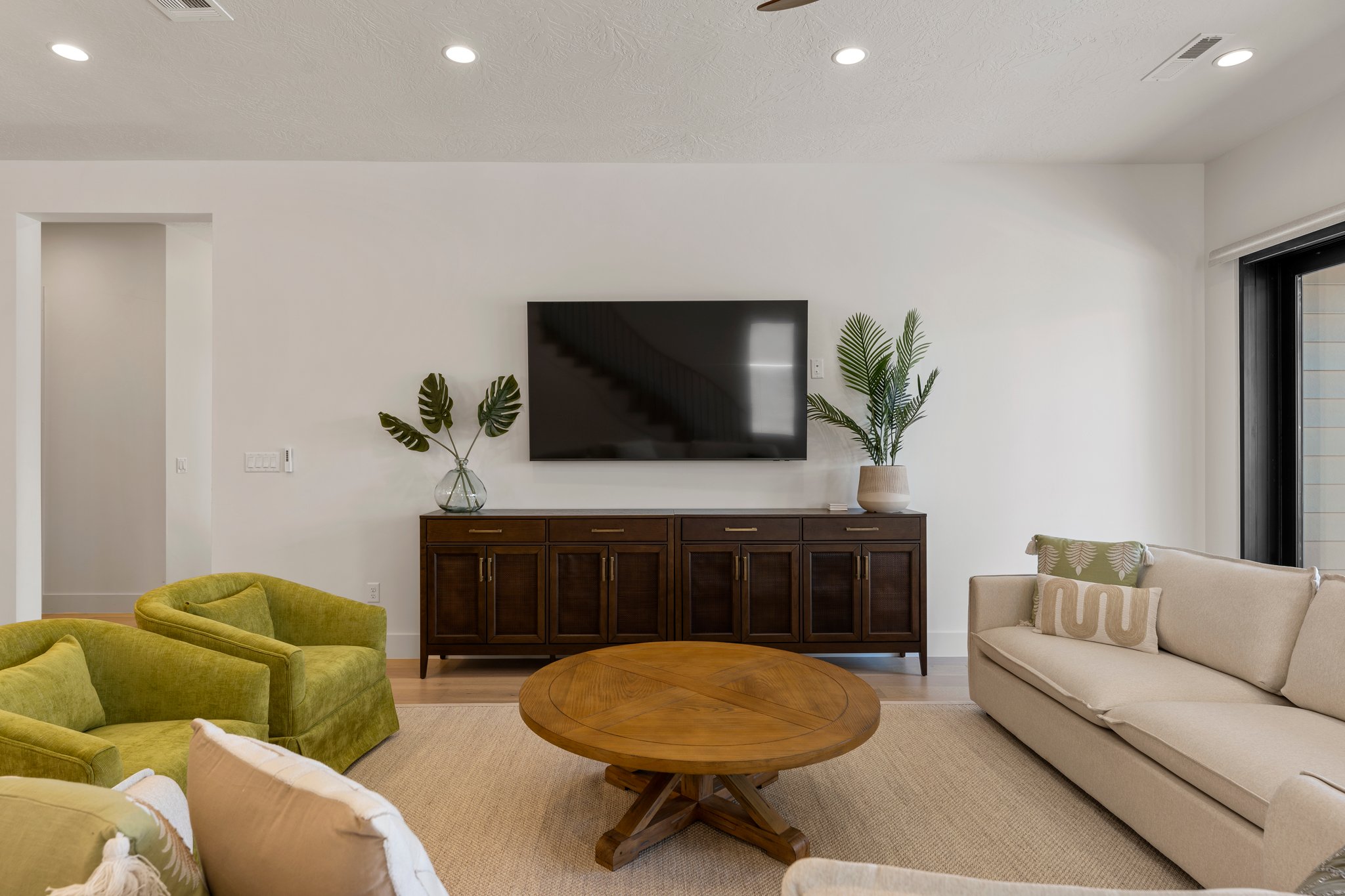 Spacious living area featuring light wood-finish flooring, recessed lighting, and a neutral color palette