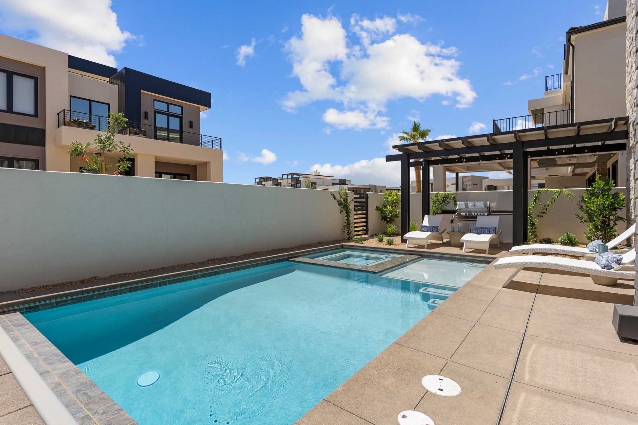 Outdoor living space featuring a swimming pool, integrated spa, and concrete decking