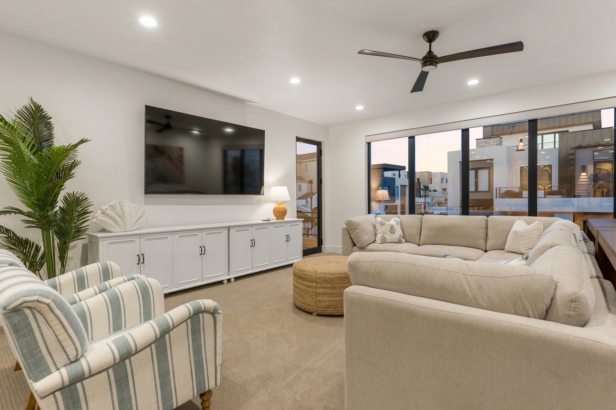 Open-concept living space with expansive floor-to-ceiling windows, recessed lighting, and a ceiling fan