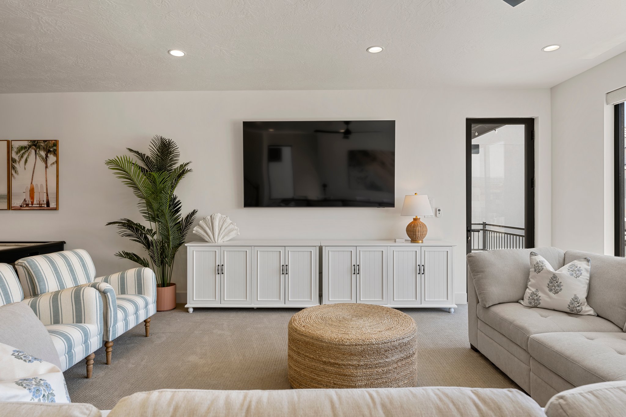 Living area featuring recessed lighting, a built-in media console, a wall-mounted television, and a glass-paned door leading to an outdoor space