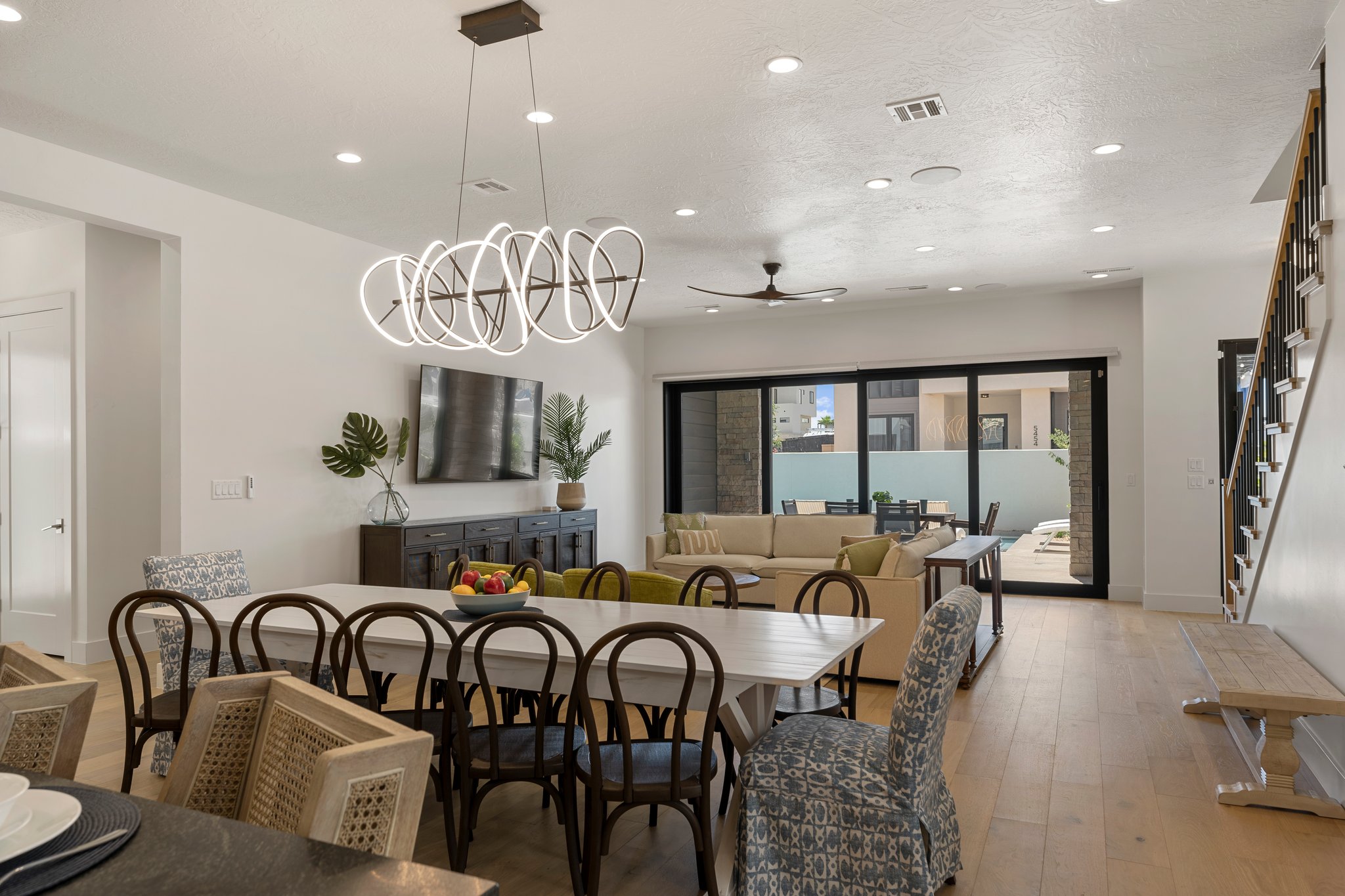 Spacious dining area featuring a linear chandelier, wood-finish flooring, and recessed lighting