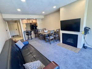 Living area featuring a fireplace with a tile hearth, recessed lighting, and carpeting