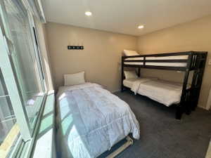 Bedroom featuring a large window, recessed lighting, wall-mounted coat rack, light-toned walls, and dark-toned carpeting