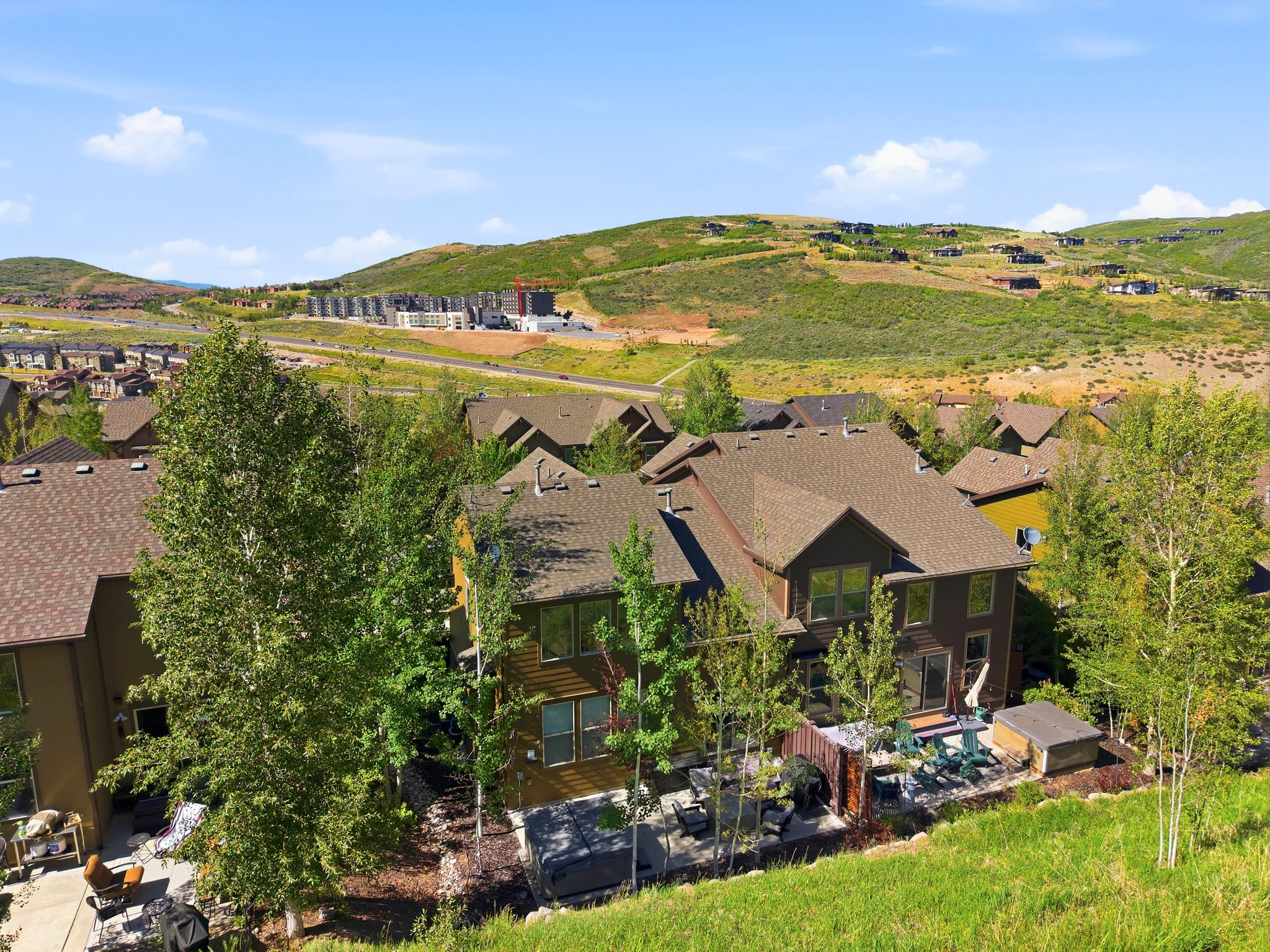 Multi-level residence featuring a brown shingle roof and dark-toned siding