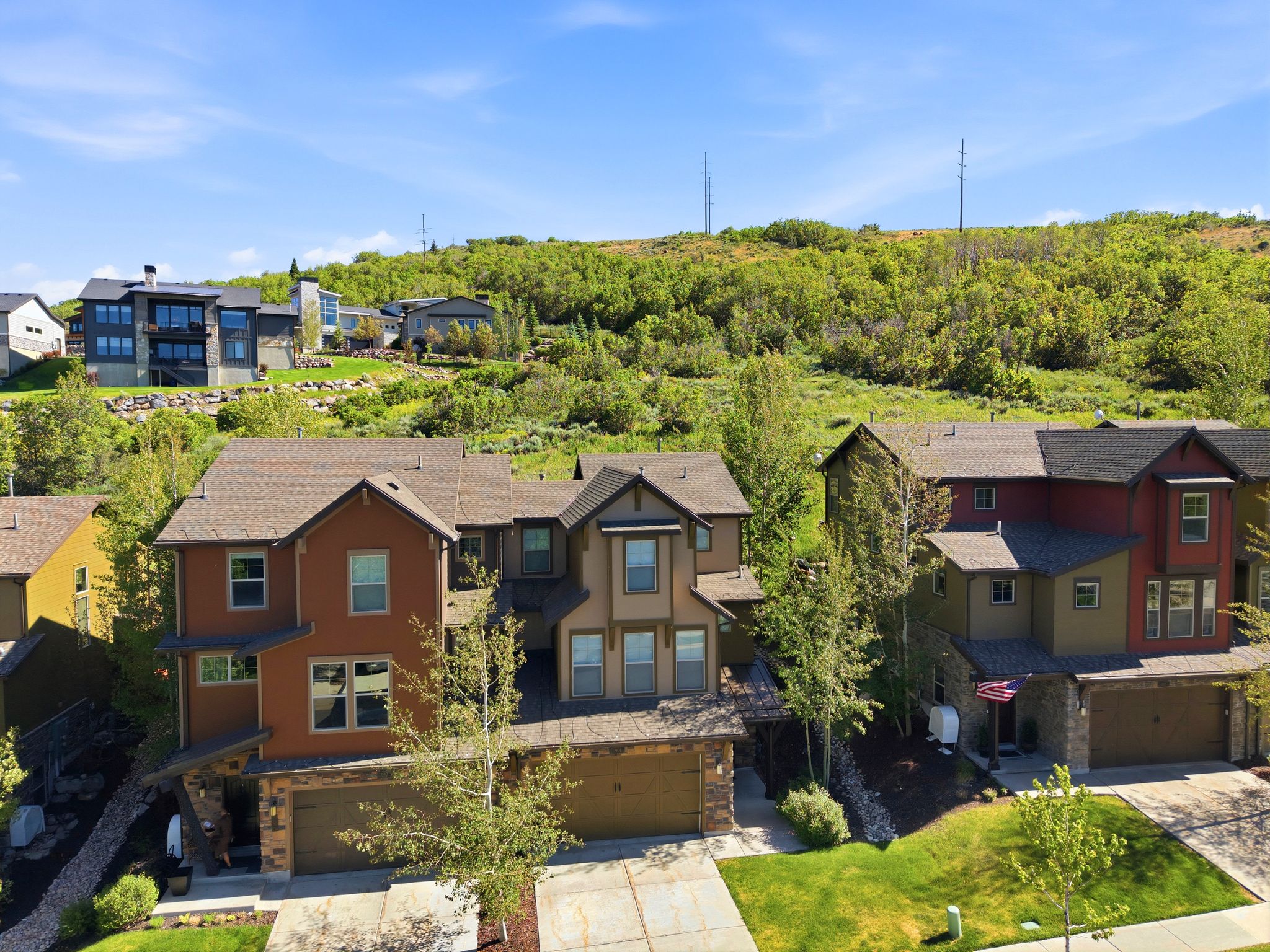Multi-story residence featuring a brown facade with contrasting trim, a two-car garage, and a concrete driveway