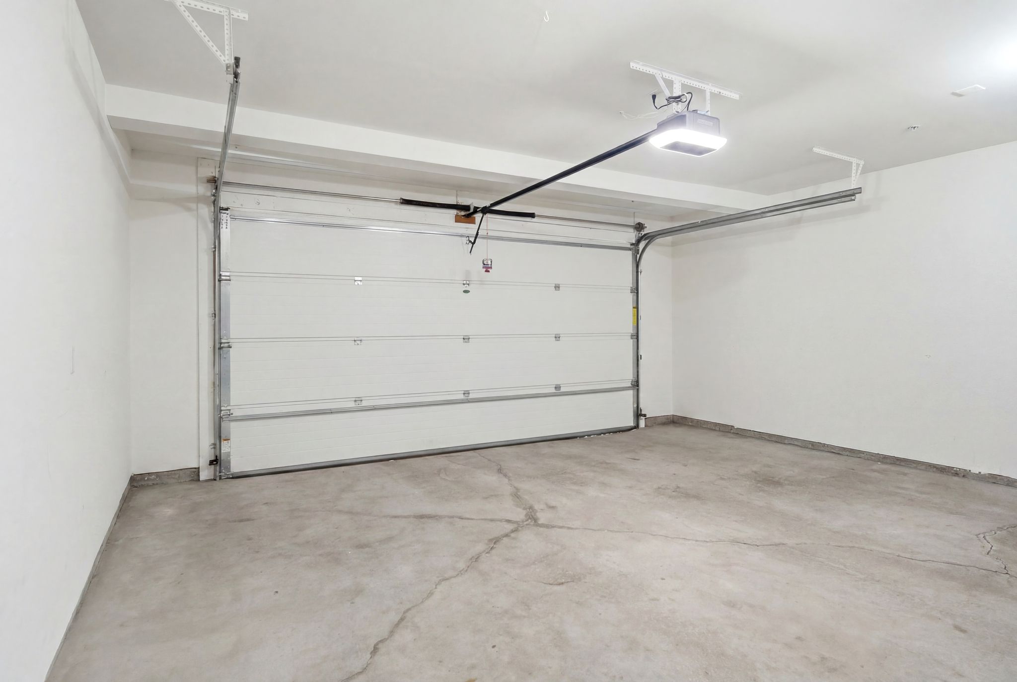 Spacious garage featuring a white overhead door, concrete flooring, and an automatic garage door opener